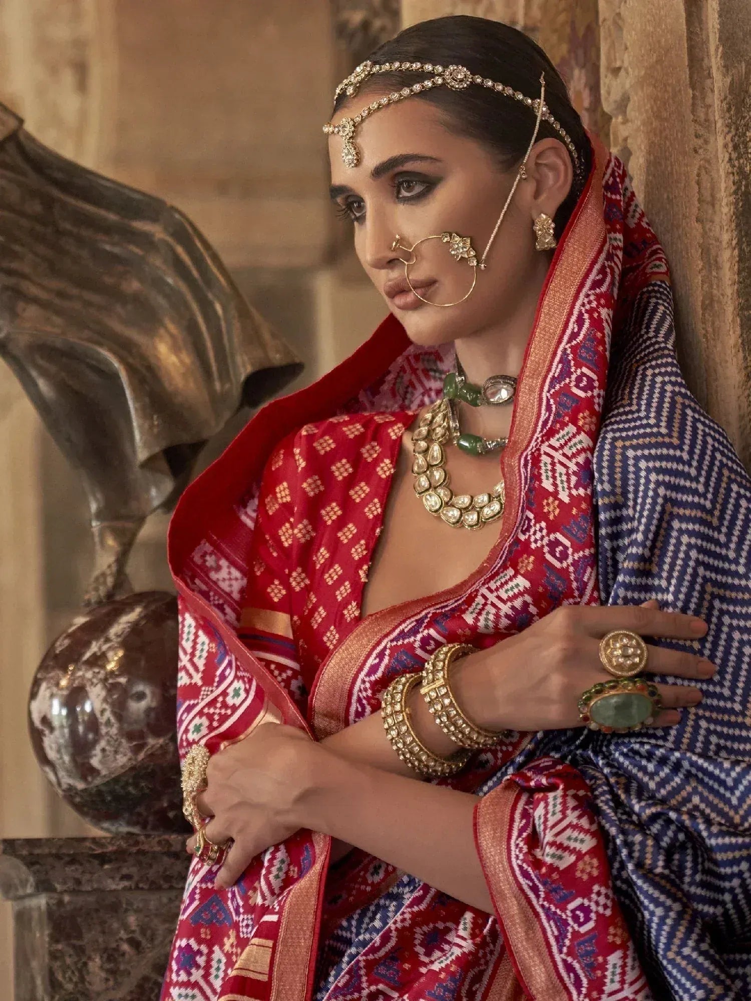 Woman in red and blue ethnic saree with gold jewelry, traditional Indian attire