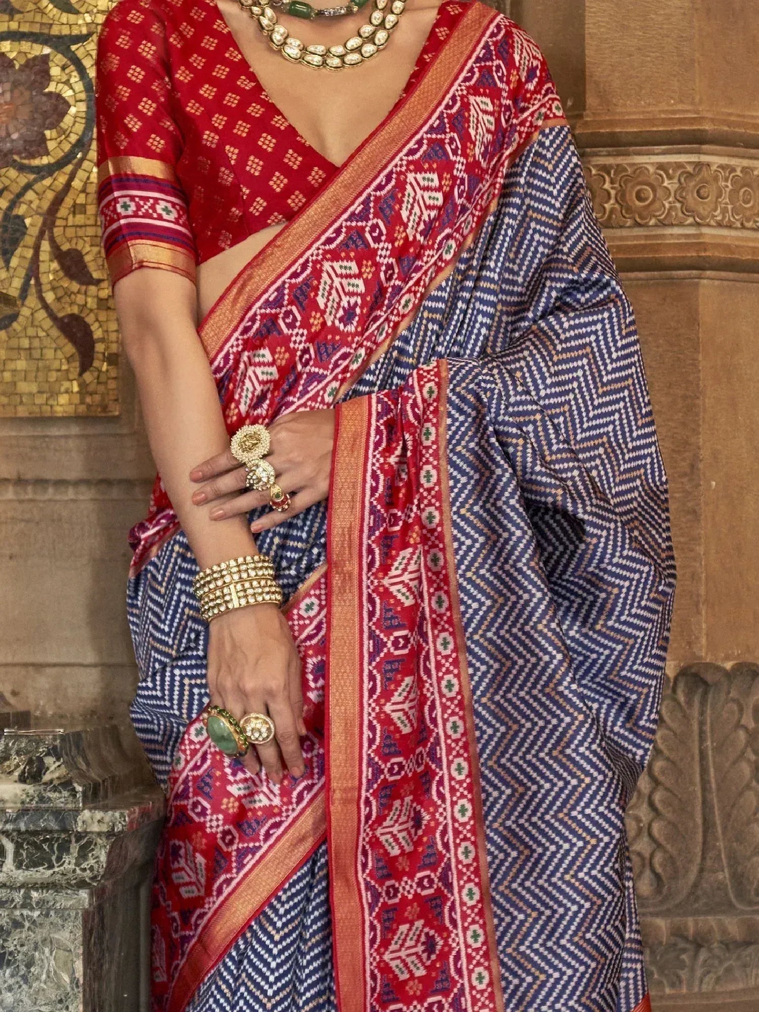 Blue and red ethnic saree with geometric patterns, paired with designer blouse and traditional jewelry