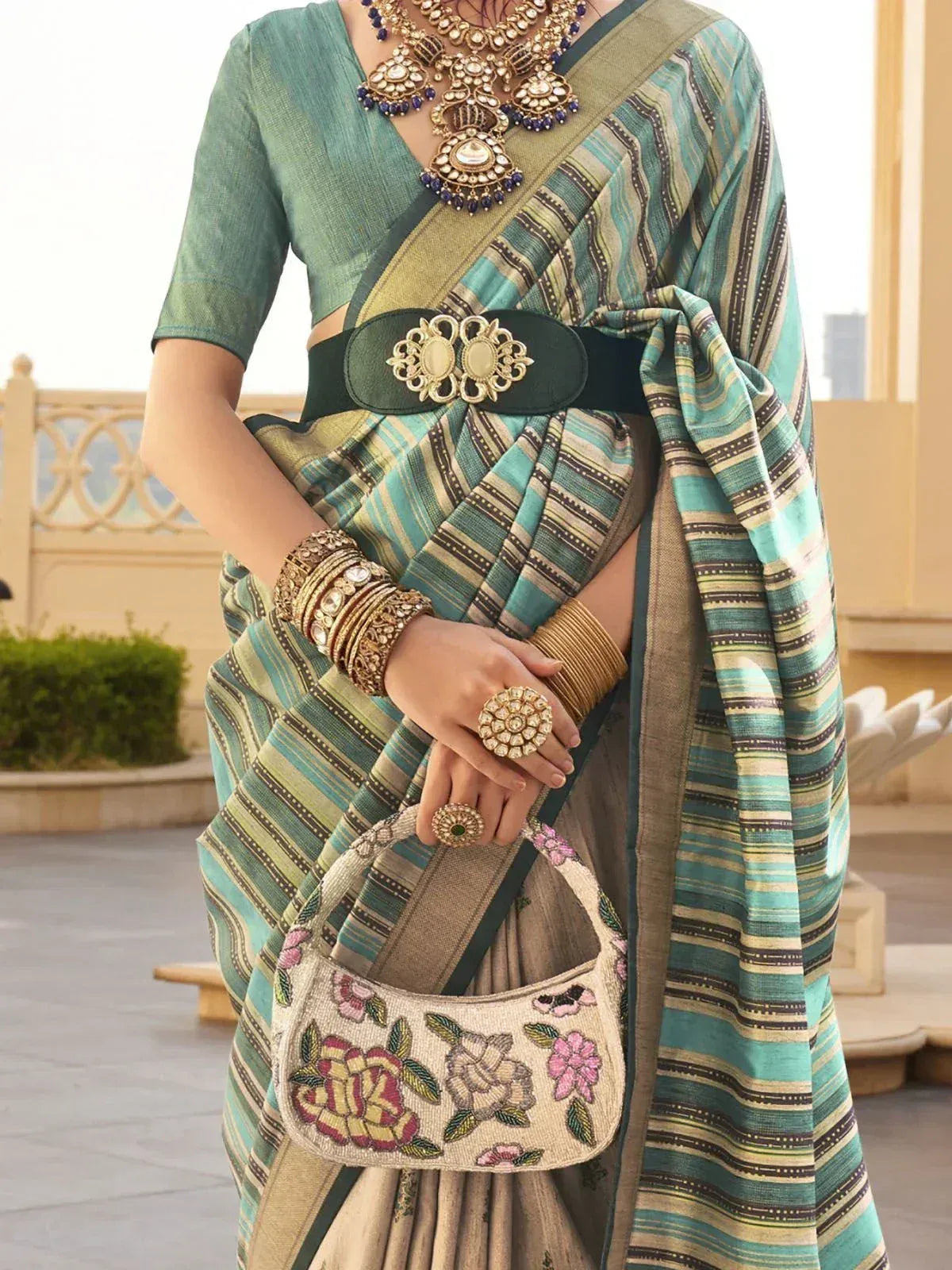 Teal and gold striped saree with embroidered floral bag, traditional Indian ethnic wear