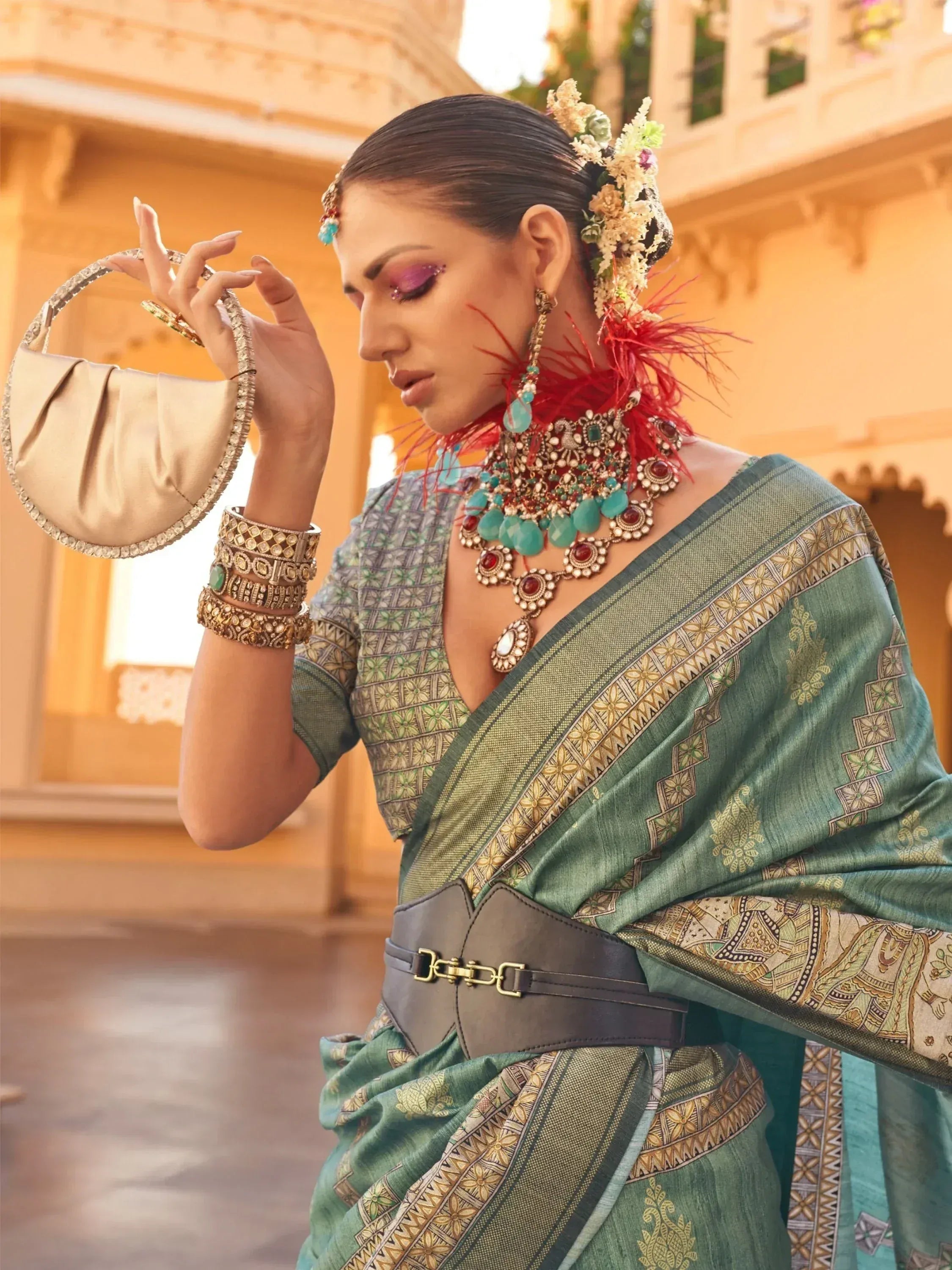 Elegant green printed saree with gold border, statement jewelry, and floral hair accessory for Indian ethnic wear.