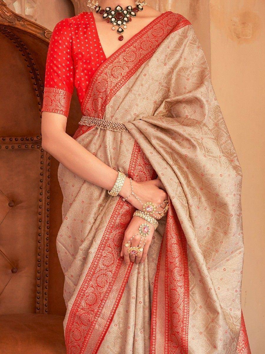 Beige and red ethnic saree with intricate border, paired with designer blouse and traditional jewelry for festive occasions