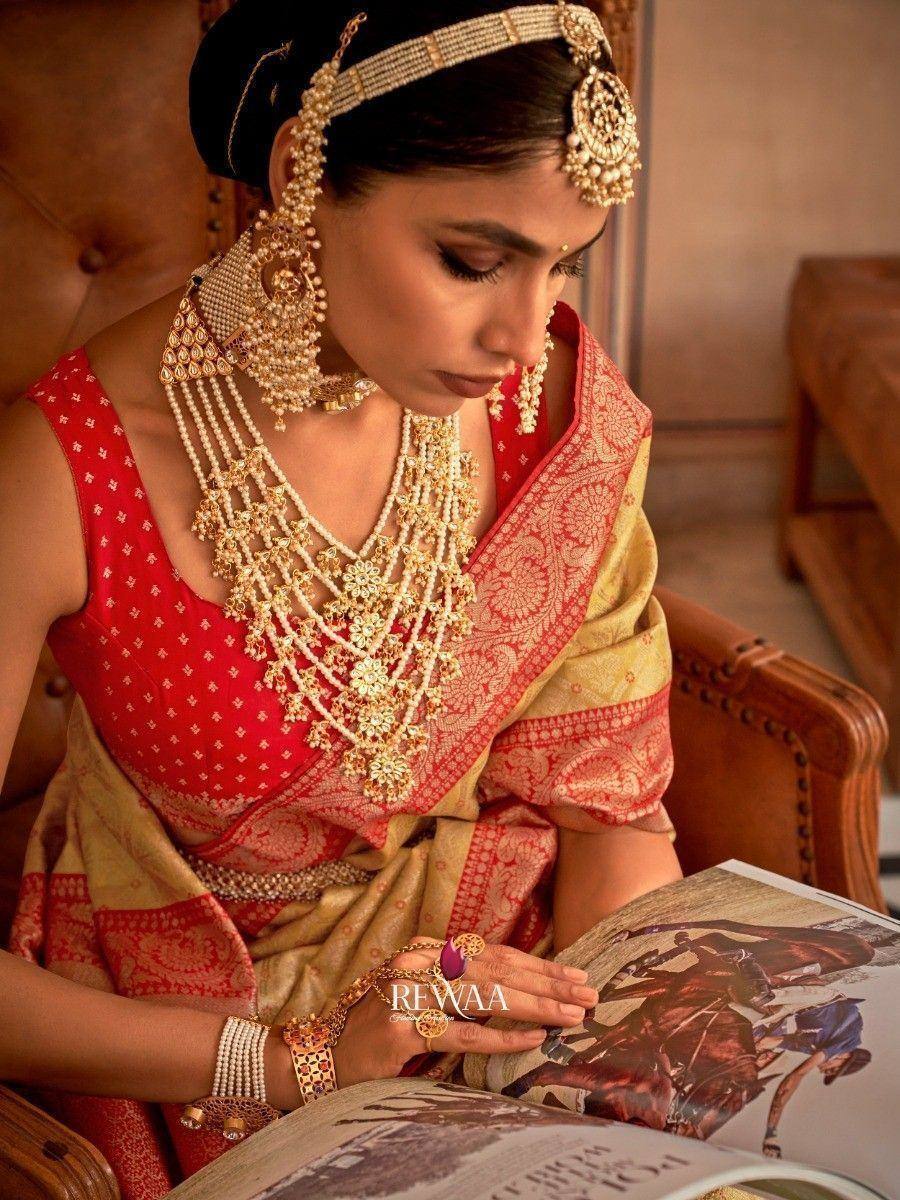 Woman in red and gold ethnic saree with traditional jewelry reading magazine