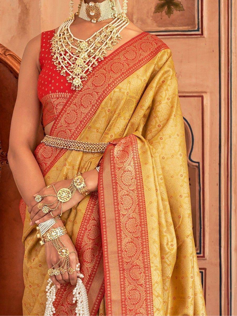 Elegant gold and red designer saree with intricate embroidery, paired with traditional Indian jewelry for festive occasions.
