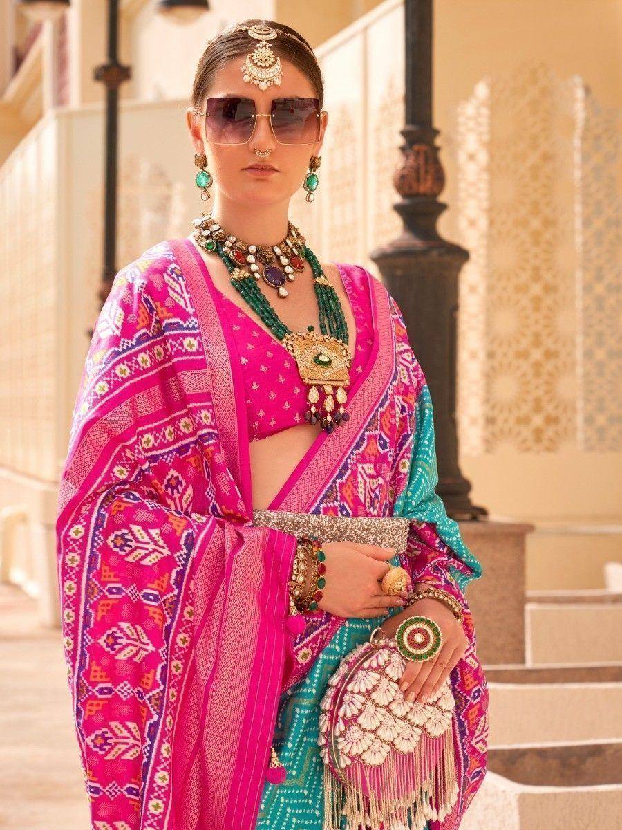 Vibrant pink and teal printed saree with ethnic jewelry, perfect for Indian festive occasions