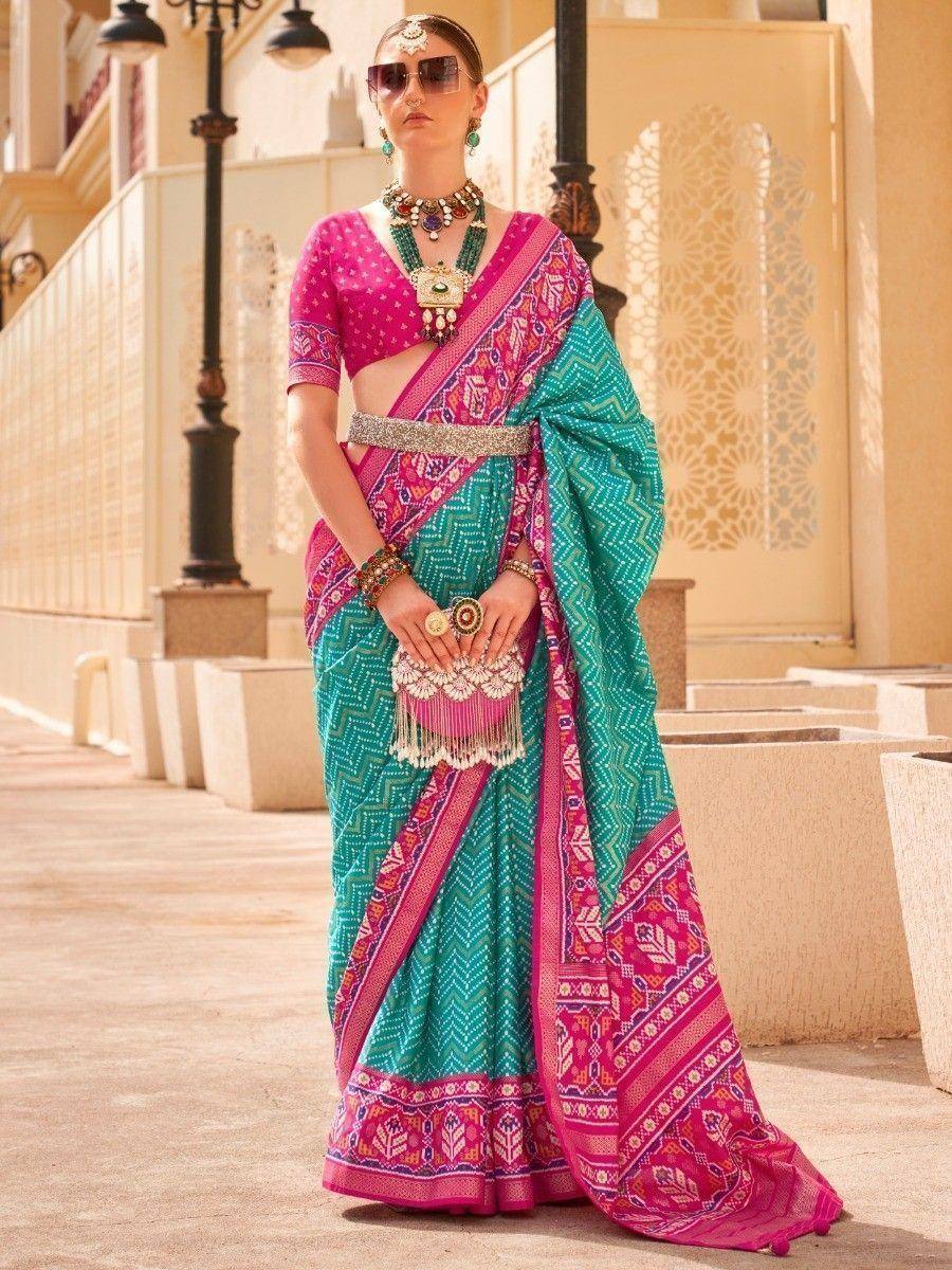Vibrant teal and pink printed saree with ethnic jewelry, perfect for Indian festive occasions
