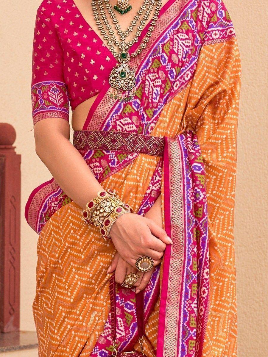 Vibrant orange and pink printed saree with ethnic jewelry, perfect for Indian festive occasions.