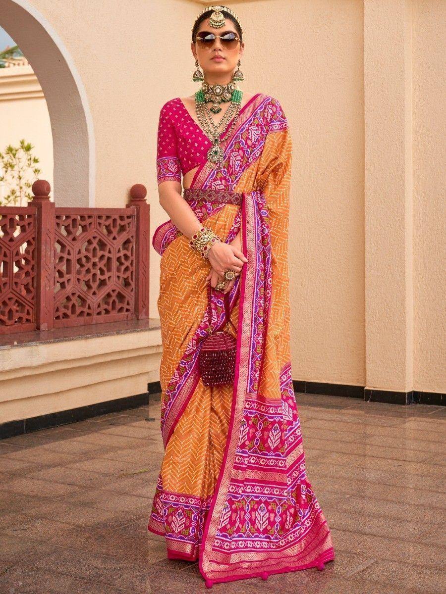 Woman in vibrant pink and orange printed saree with traditional jewelry, perfect for ethnic occasions