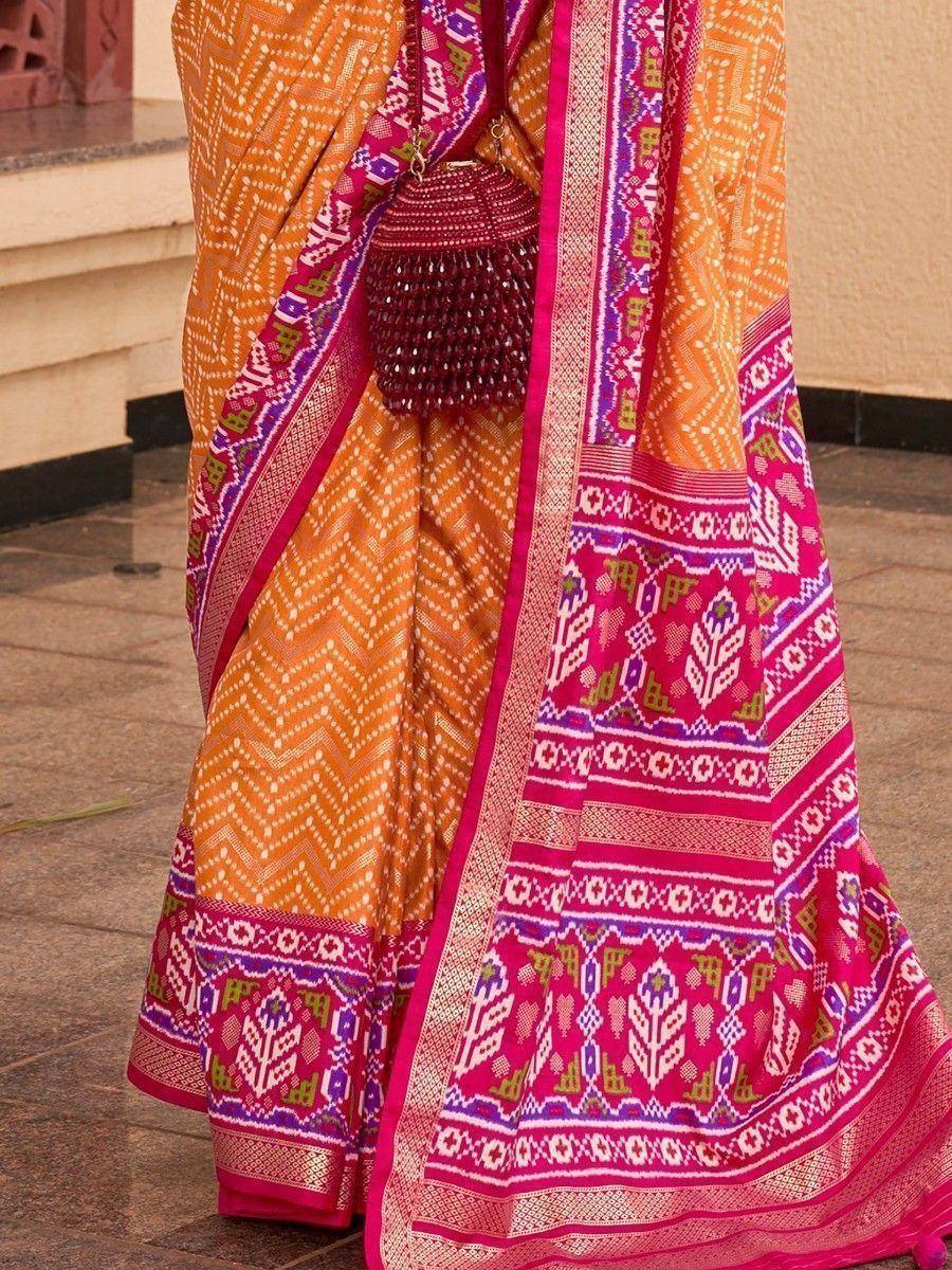 Orange and pink ethnic saree with geometric patterns and beaded clutch, perfect for Indian occasions.