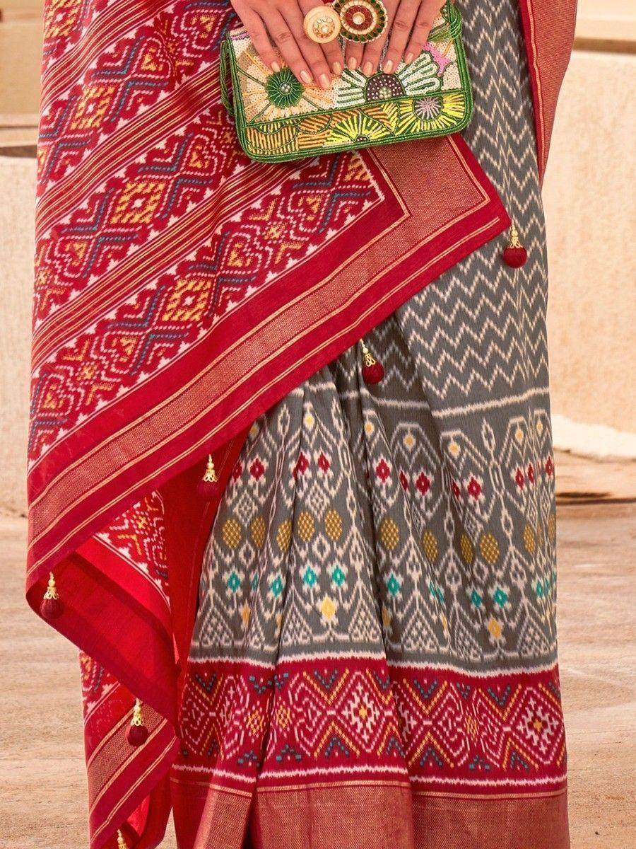 Grey and red ethnic saree with geometric print, tassels, and embroidered clutch