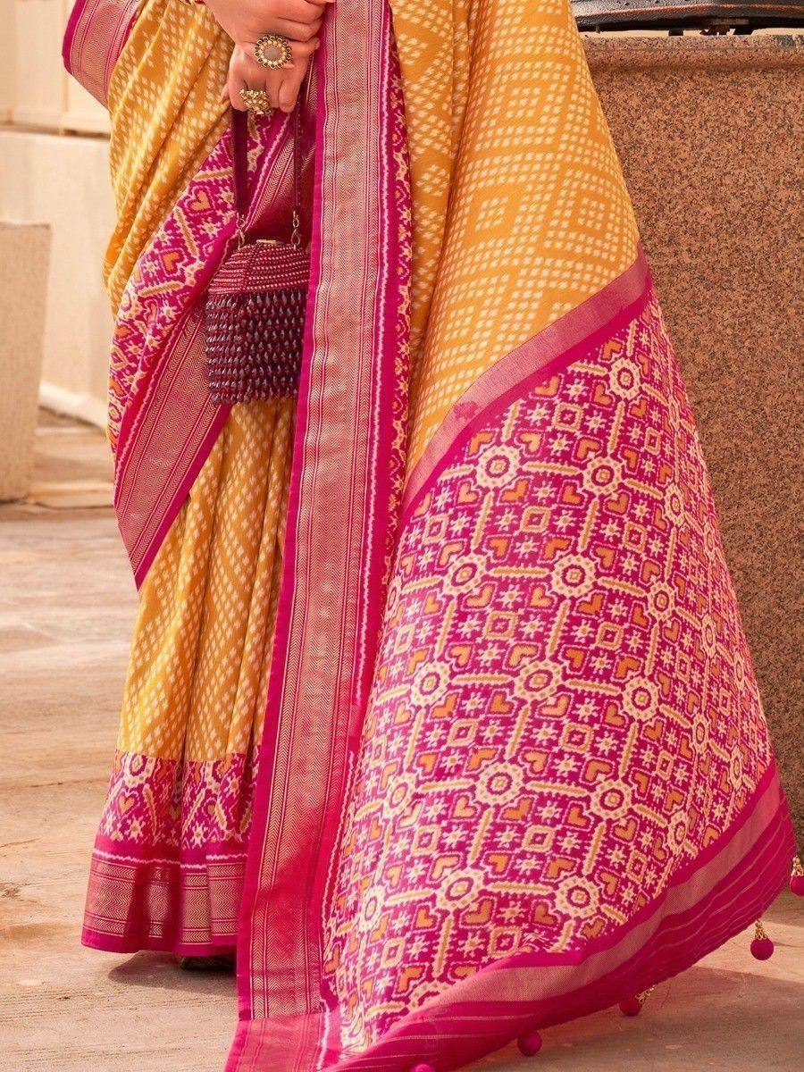 Yellow and pink ethnic saree with geometric print and tassels, styled with matching blouse and handbag