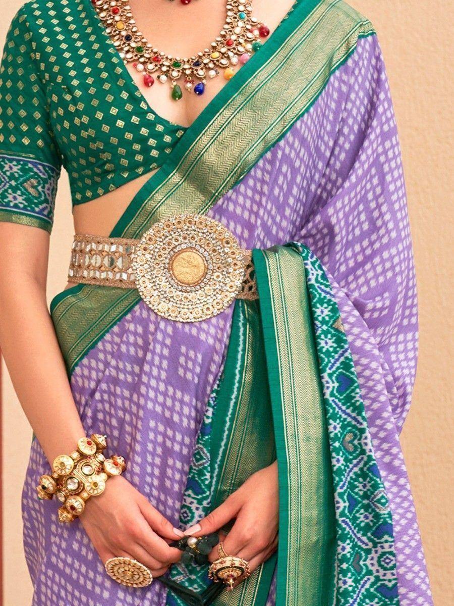 Purple and green ethnic saree with printed pattern, embellished belt, and traditional jewelry