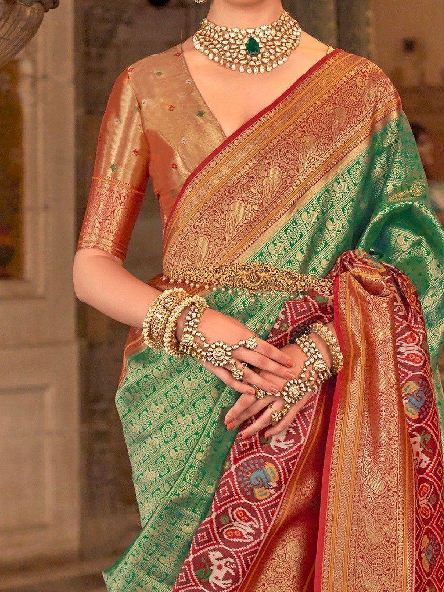 Green and red designer saree with gold embroidery, paired with traditional Indian jewelry for festive occasions