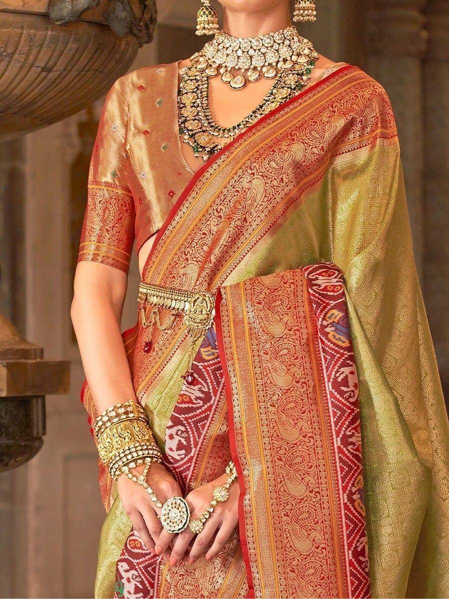 Elegant Indian saree with intricate red and gold patterns, paired with traditional jewelry