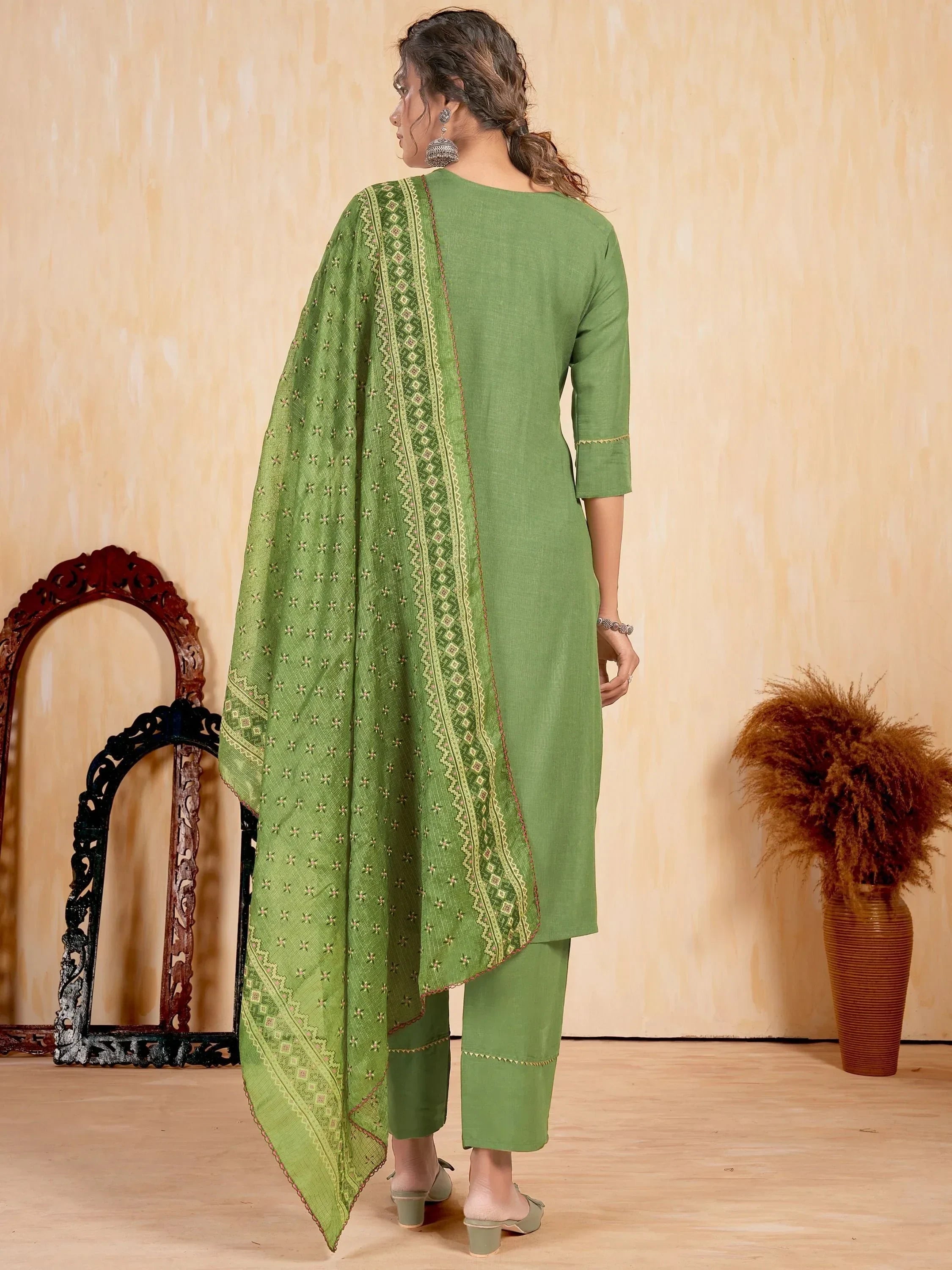 Woman wearing green embroidered salwar kameez with dupatta, back view