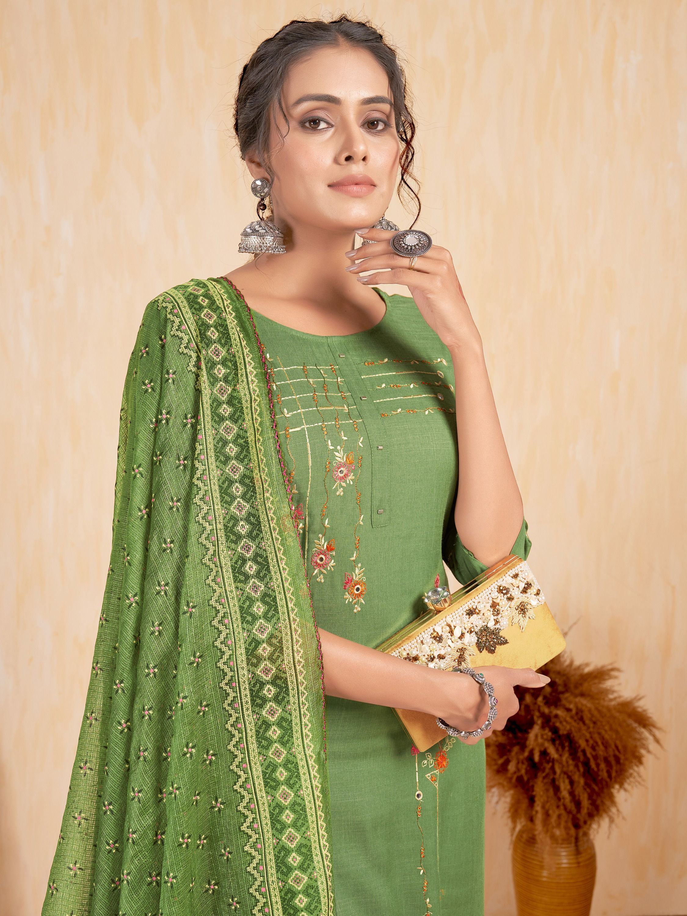 Woman in green embroidered salwar kameez with matching dupatta and ethnic jewelry