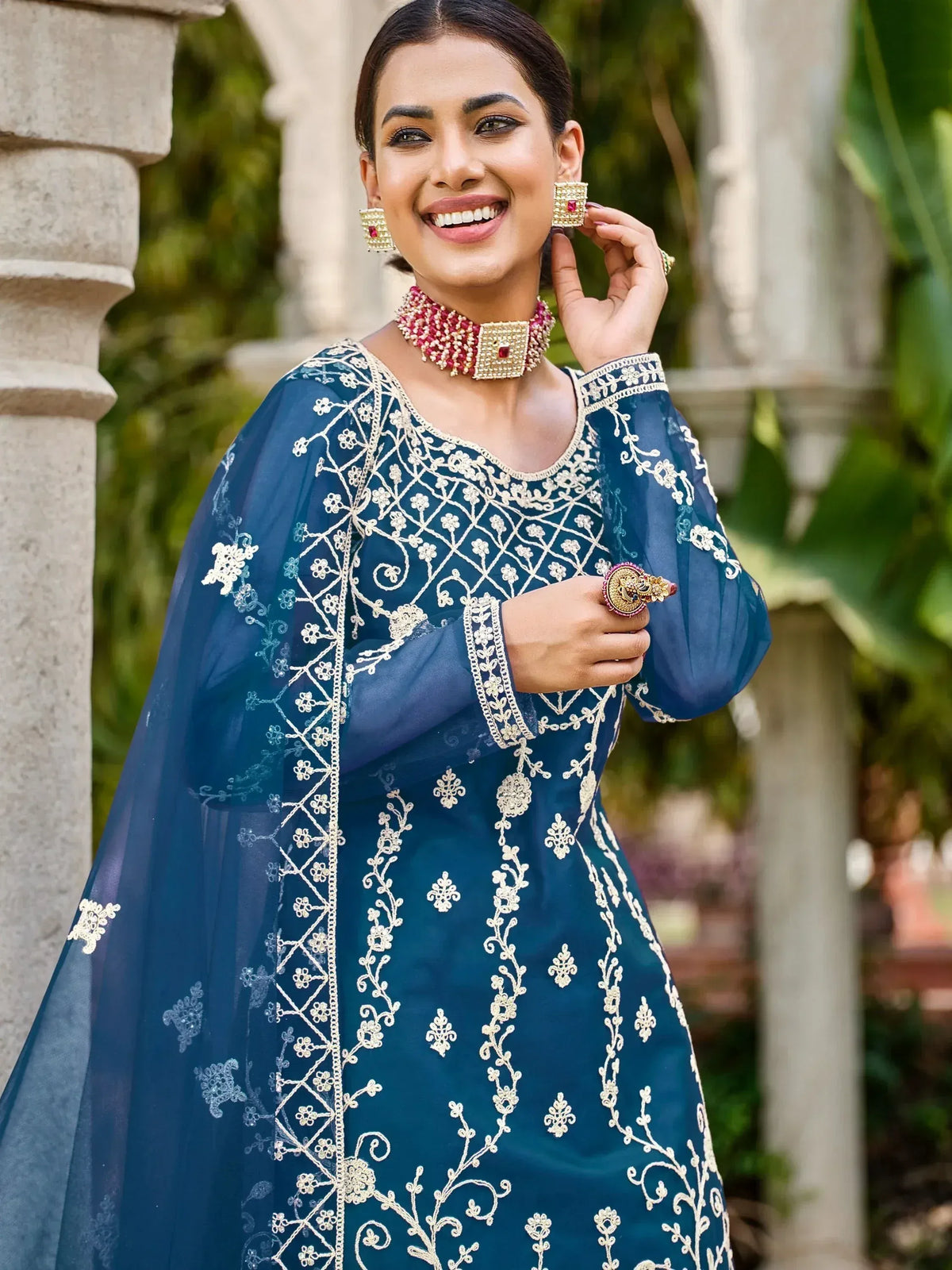 Woman in blue embroidered ethnic gown with gold floral detailing and matching jewelry