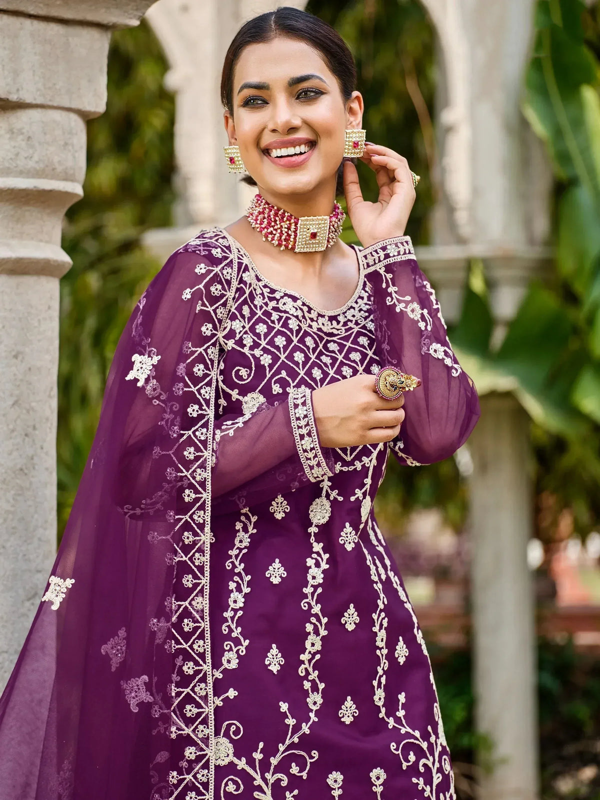 Purple embroidered ethnic gown with floral detailing, paired with statement jewelry for festive occasions