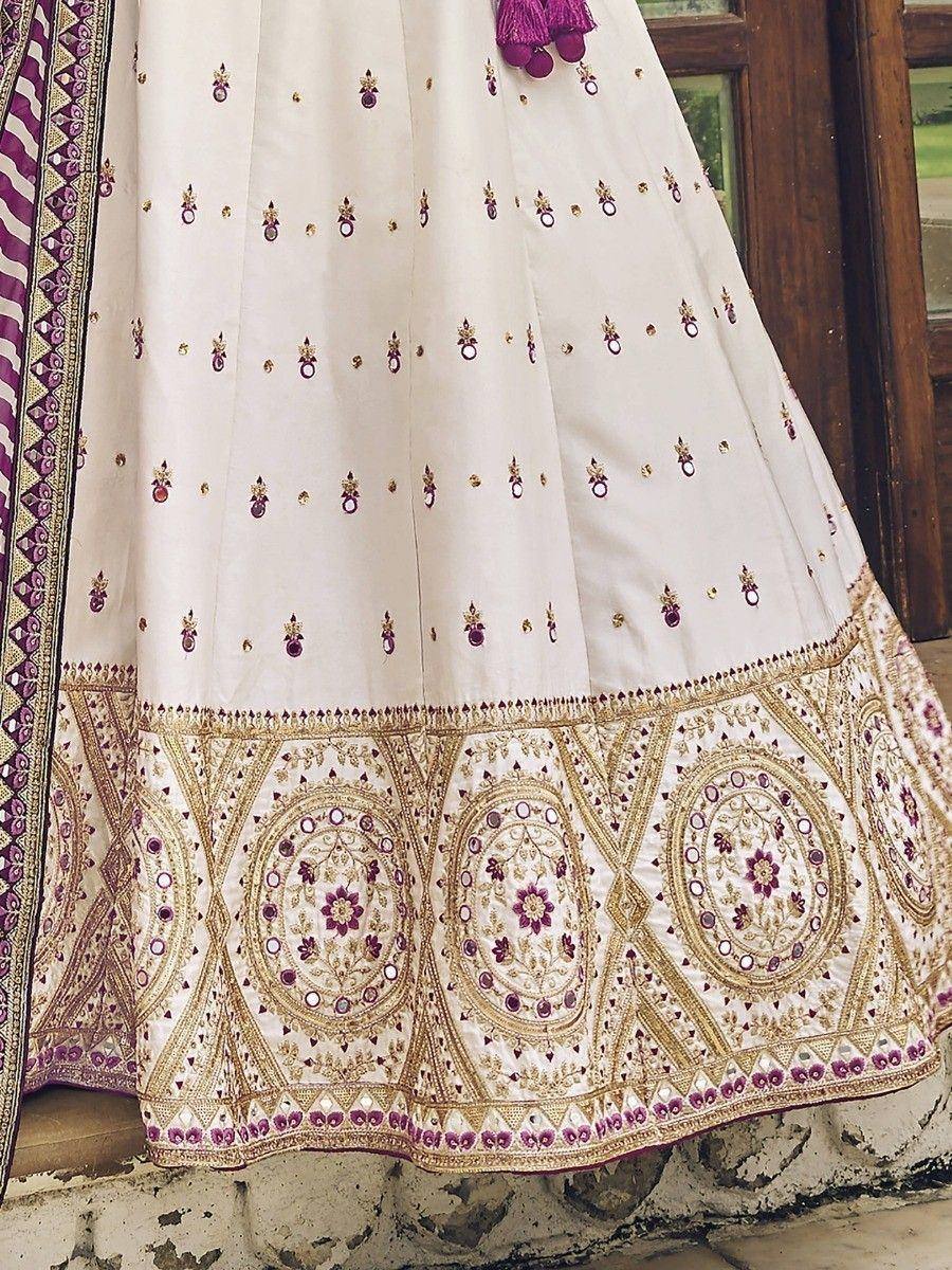 White lehenga with purple and gold embroidery, floral motifs, and mirror work, ideal for Indian ethnic wear.