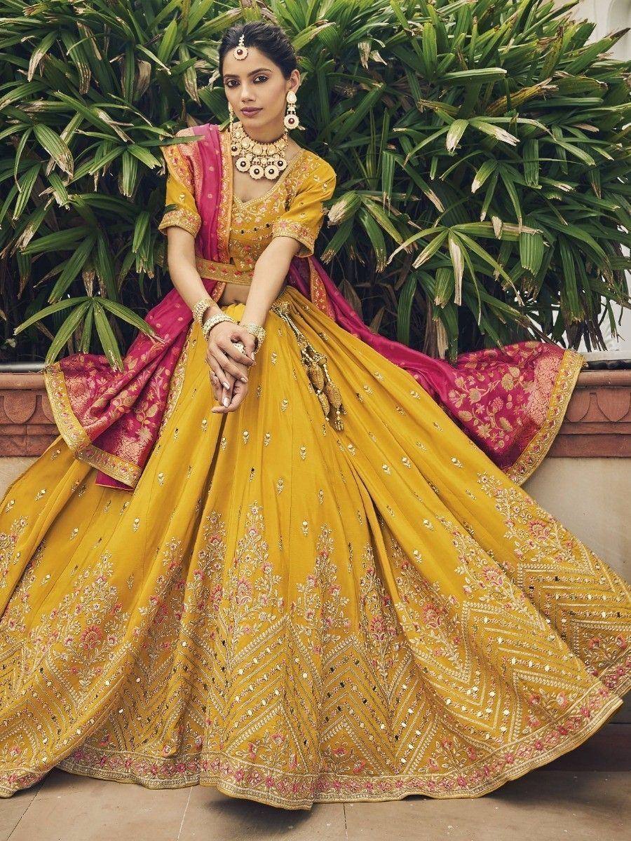 Yellow and pink embroidered lehenga choli with gold jewelry, perfect for Indian weddings and festivals
