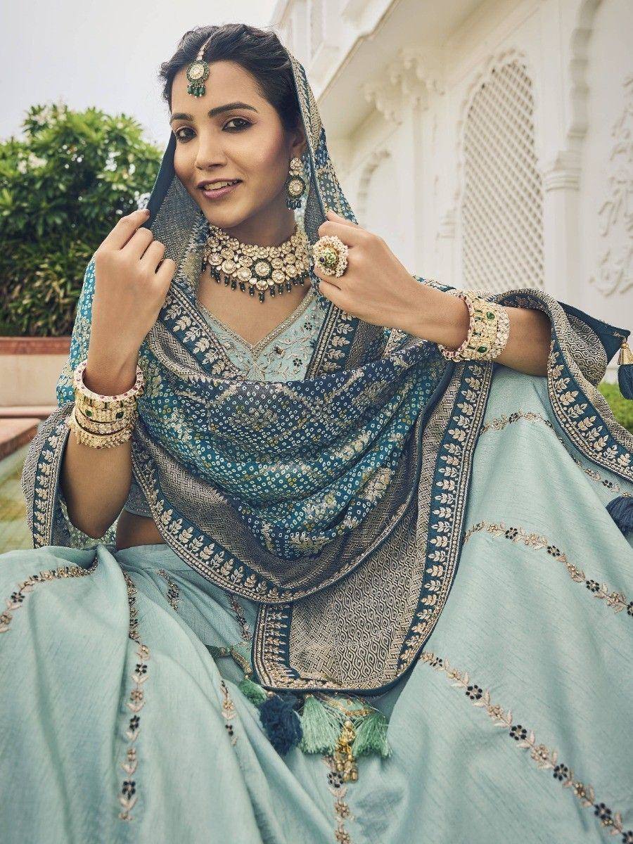 Elegant light blue lehenga choli with intricate embroidery and matching dupatta, styled with traditional Indian jewelry.