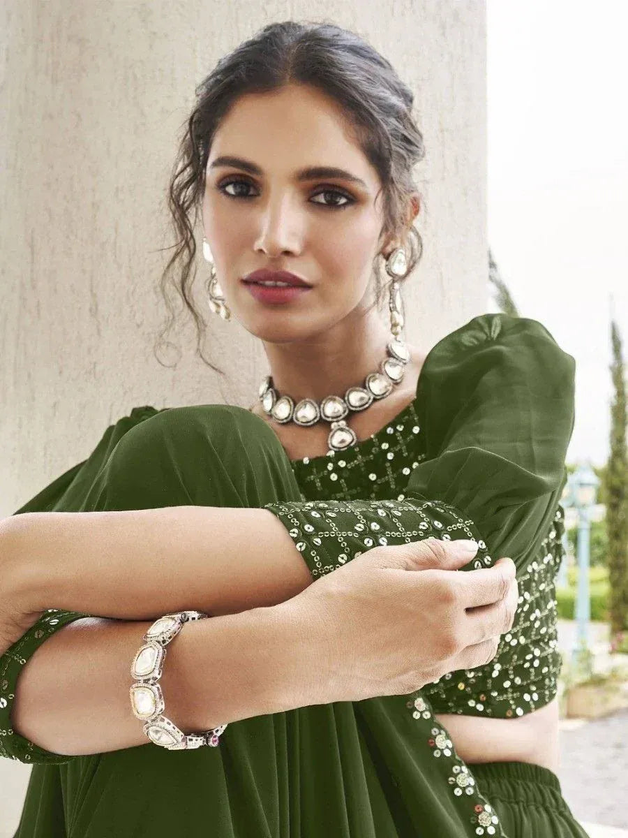 Woman in olive green ethnic gown with sequin detailing, statement jewelry, and puff sleeves