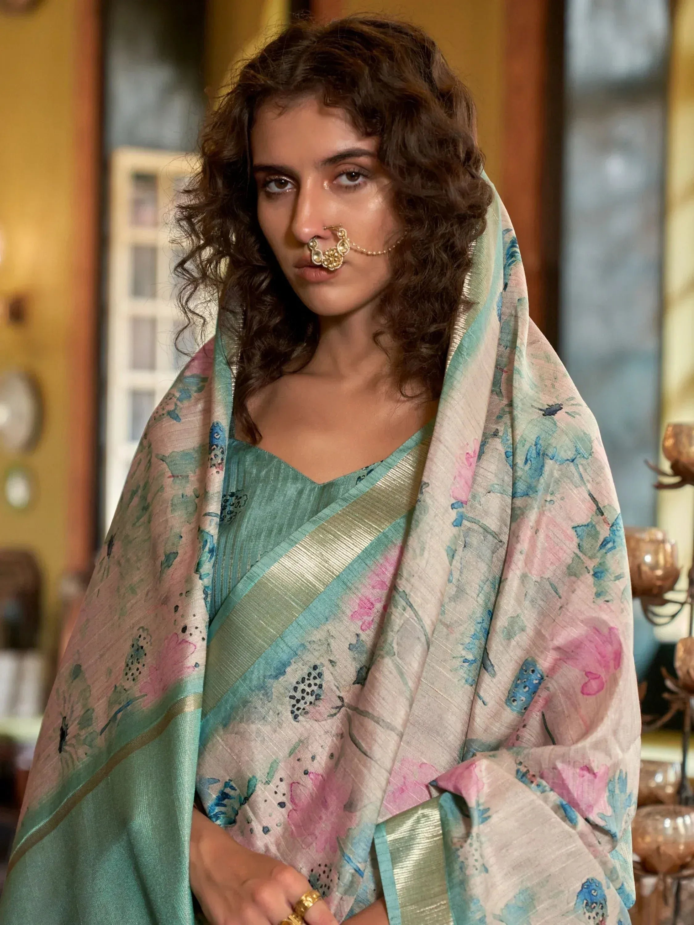 Woman in floral printed saree with gold border, traditional nose ring, ethnic Indian wear