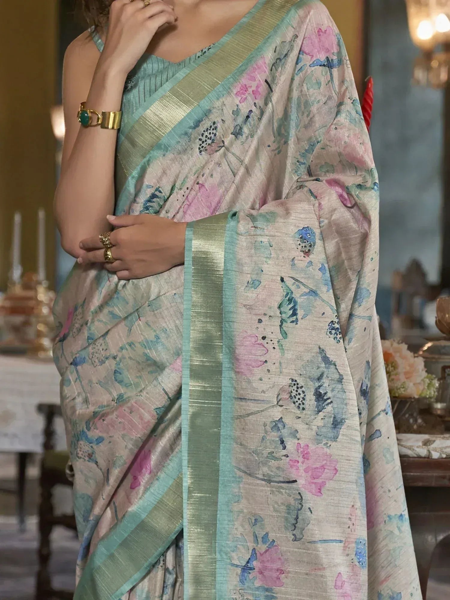 Floral printed saree with pastel pink and blue hues, gold border, and elegant drape for ethnic wear