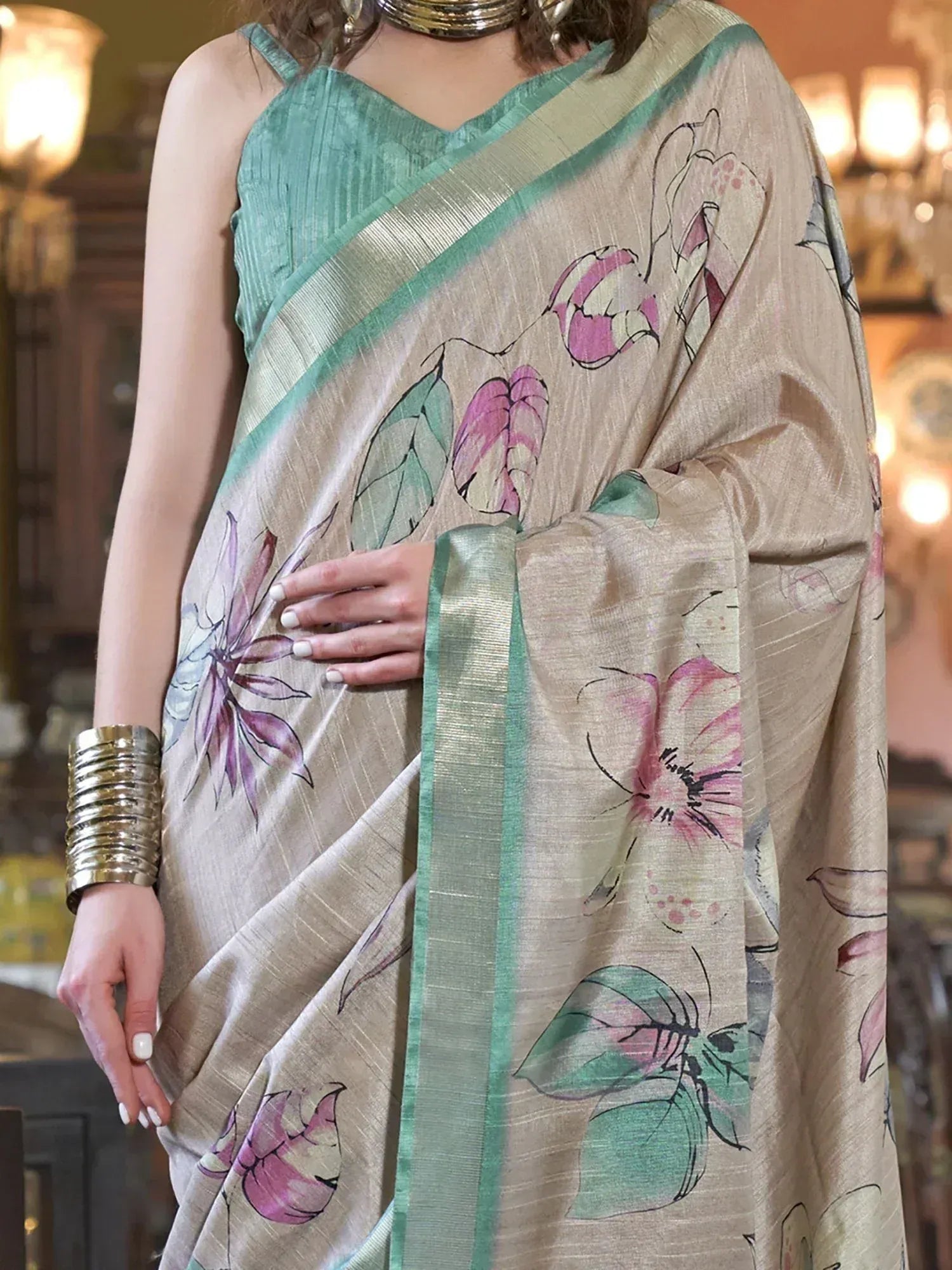 Beige saree with pink floral print and mint green border, paired with matching sleeveless blouse