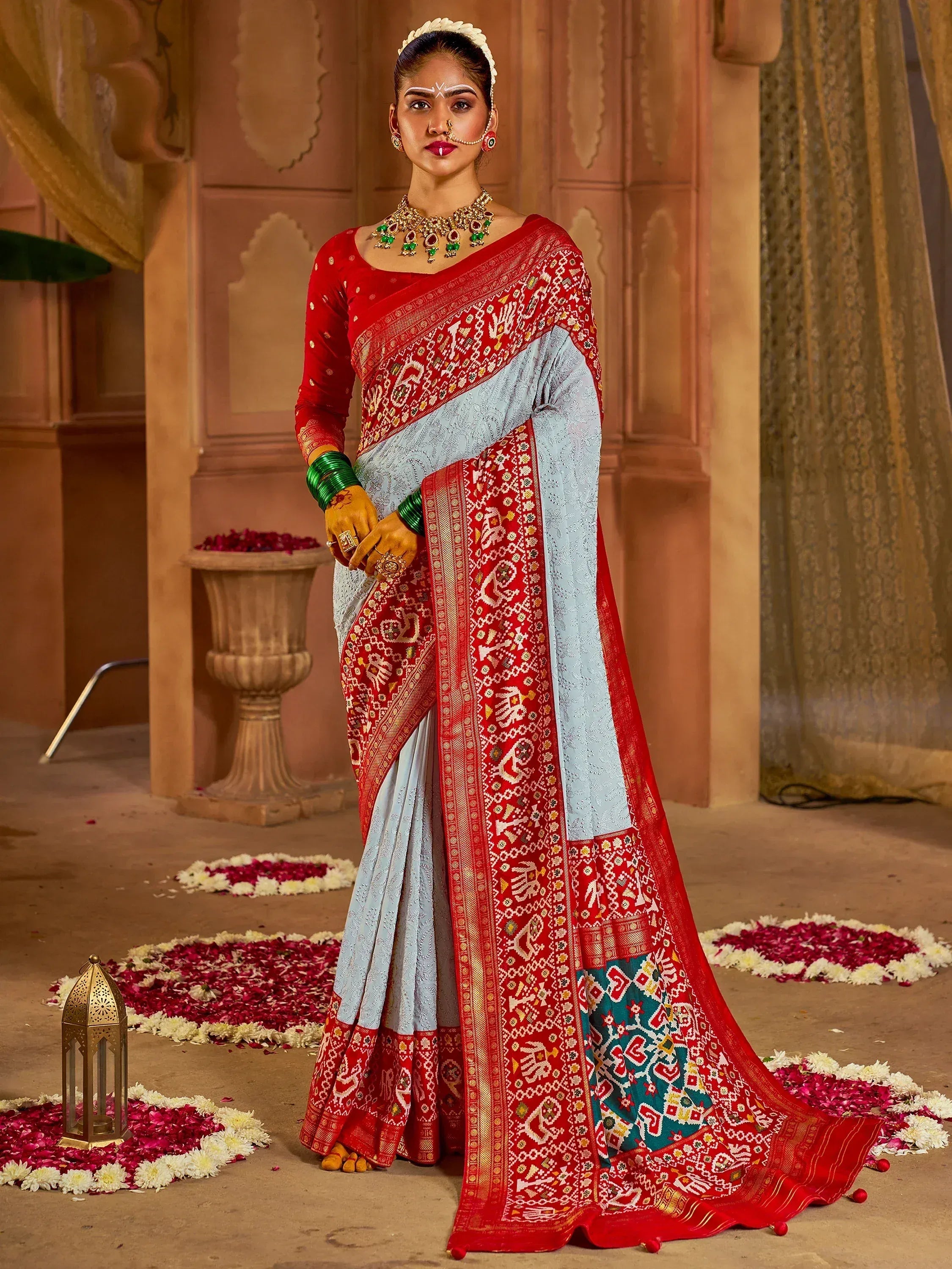 Red and light blue embroidered saree with traditional Indian wedding jewelry and floral decor