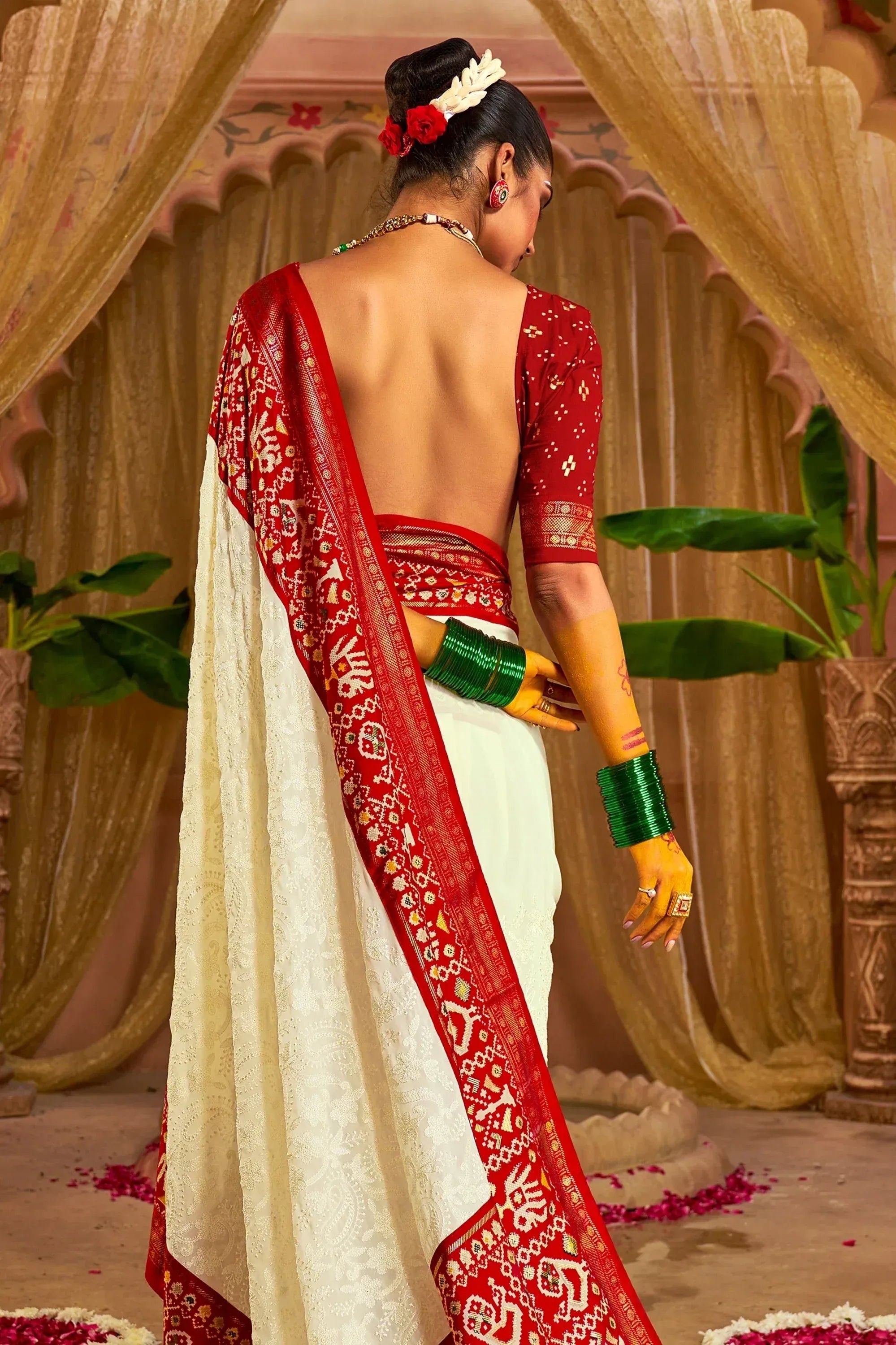 Red and white embroidered saree with backless blouse, green bangles, floral hair accessories, traditional Indian ethnic wear