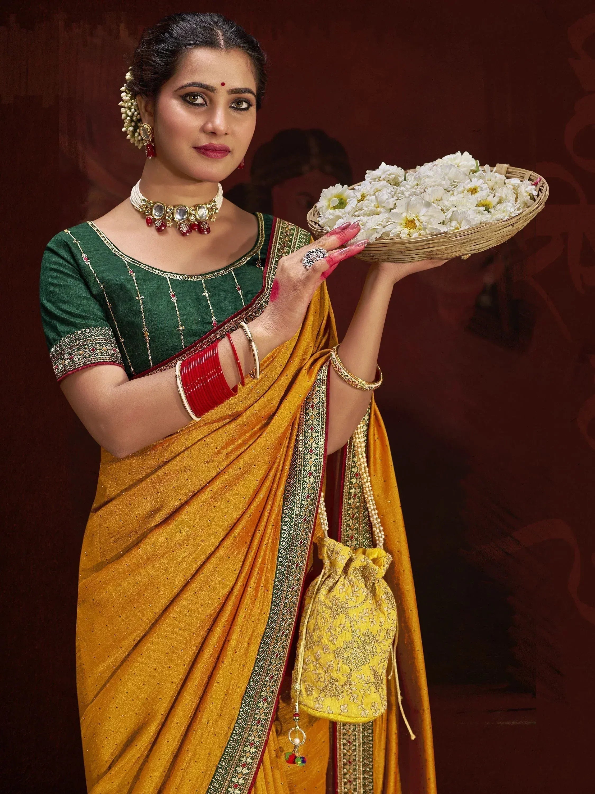 Woman in traditional Indian saree with green blouse, holding basket of white flowers, adorned with jewelry