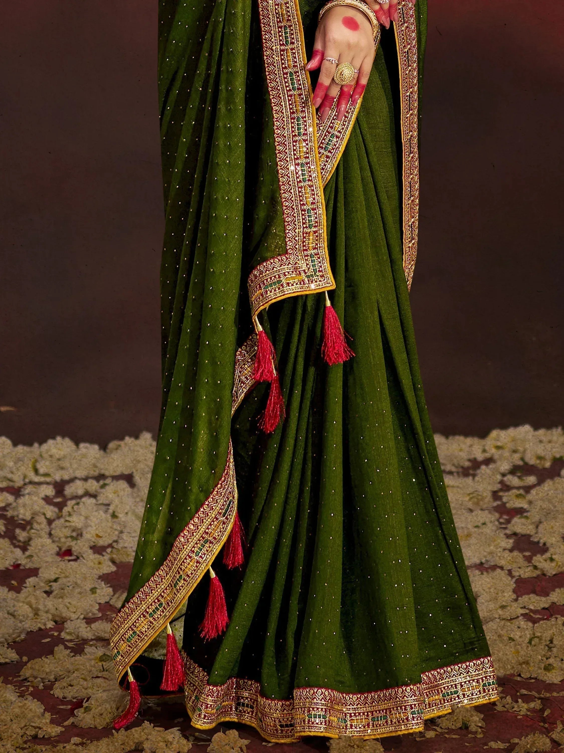 Emerald green designer saree with gold embroidery, red tassels, and sequin details for Indian ethnic wear
