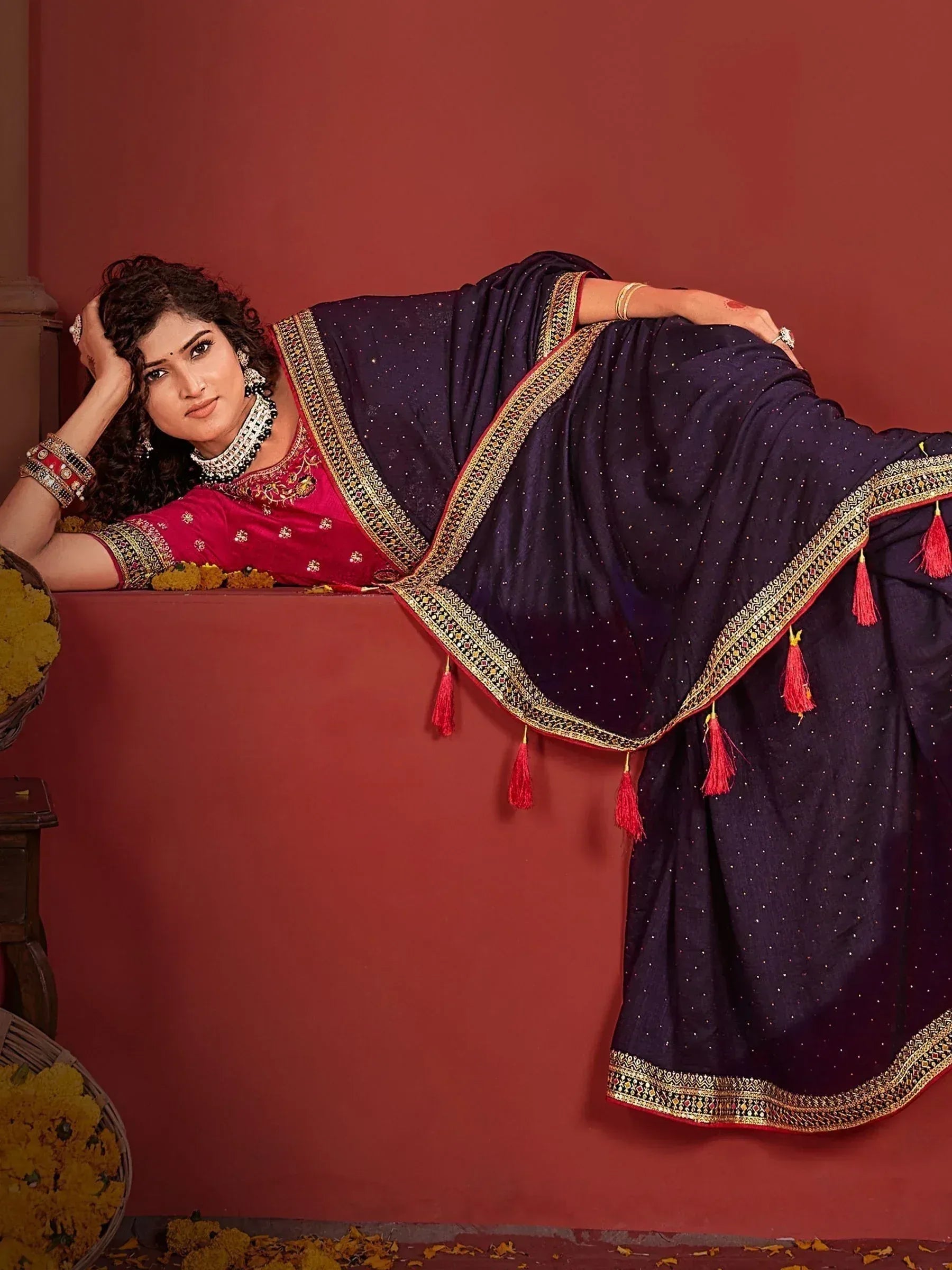 Woman in navy blue saree with gold border and red tassels, paired with pink embroidered blouse, traditional Indian ethnic wear.