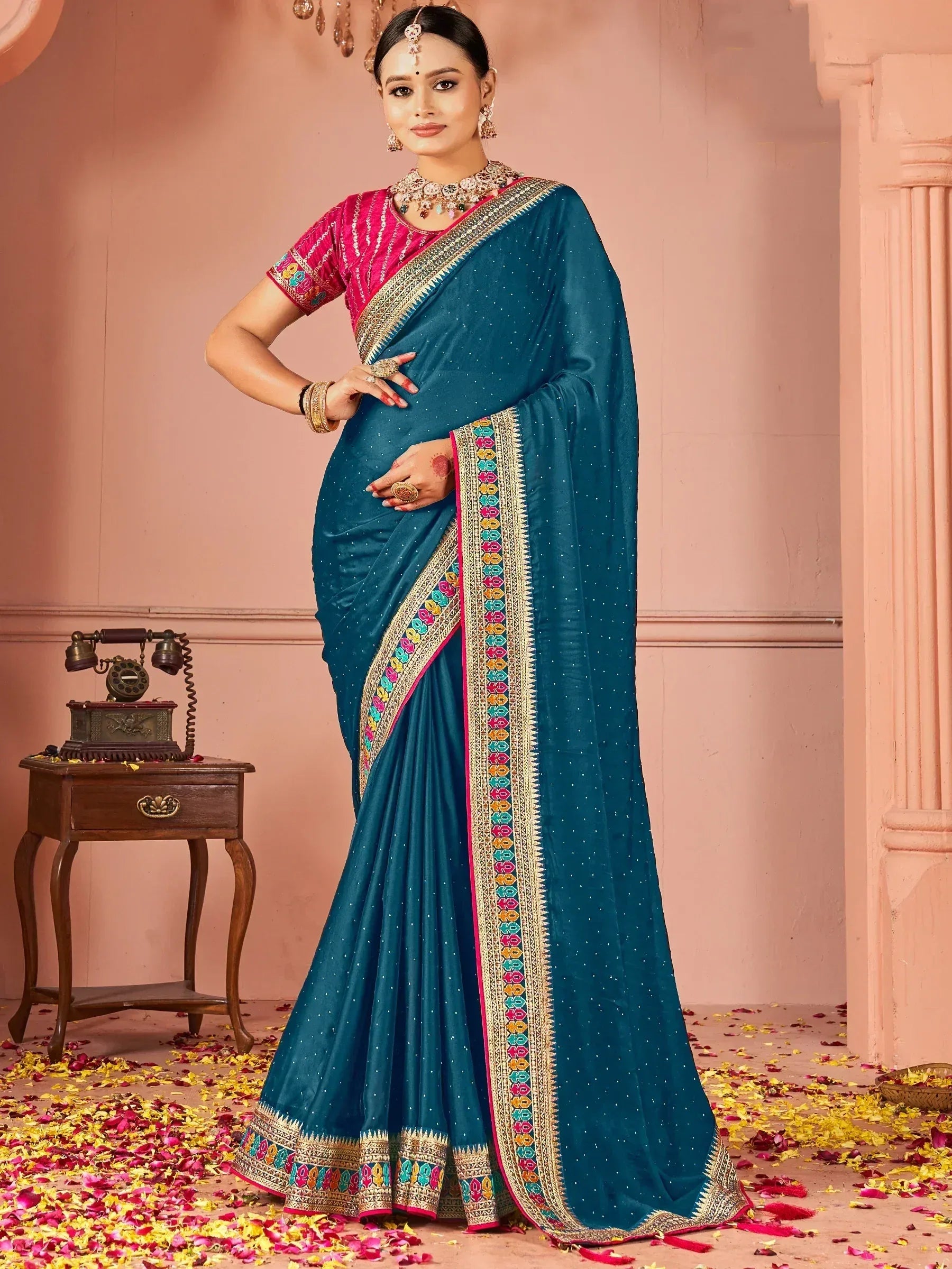 Teal saree with colorful border and pink blouse, styled with traditional jewelry for festive occasions