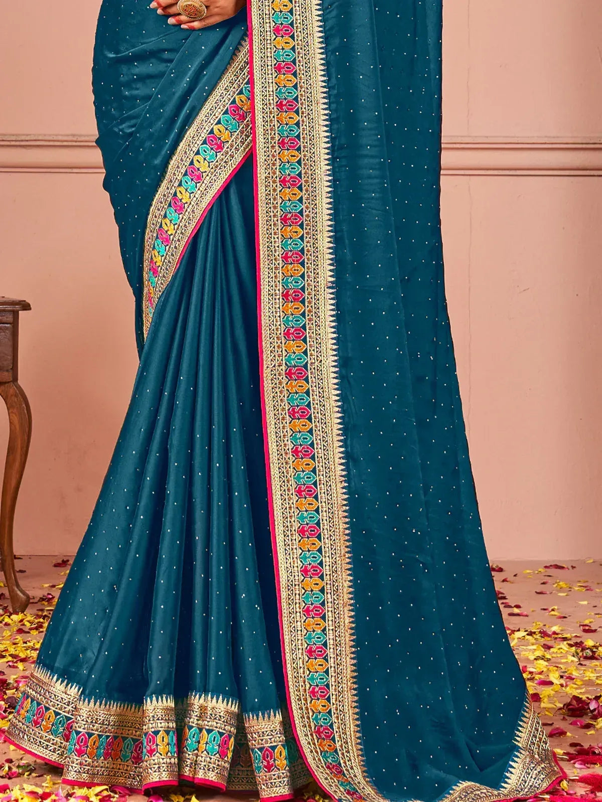 Teal saree with colorful embroidered border and gold detailing, perfect for ethnic occasions