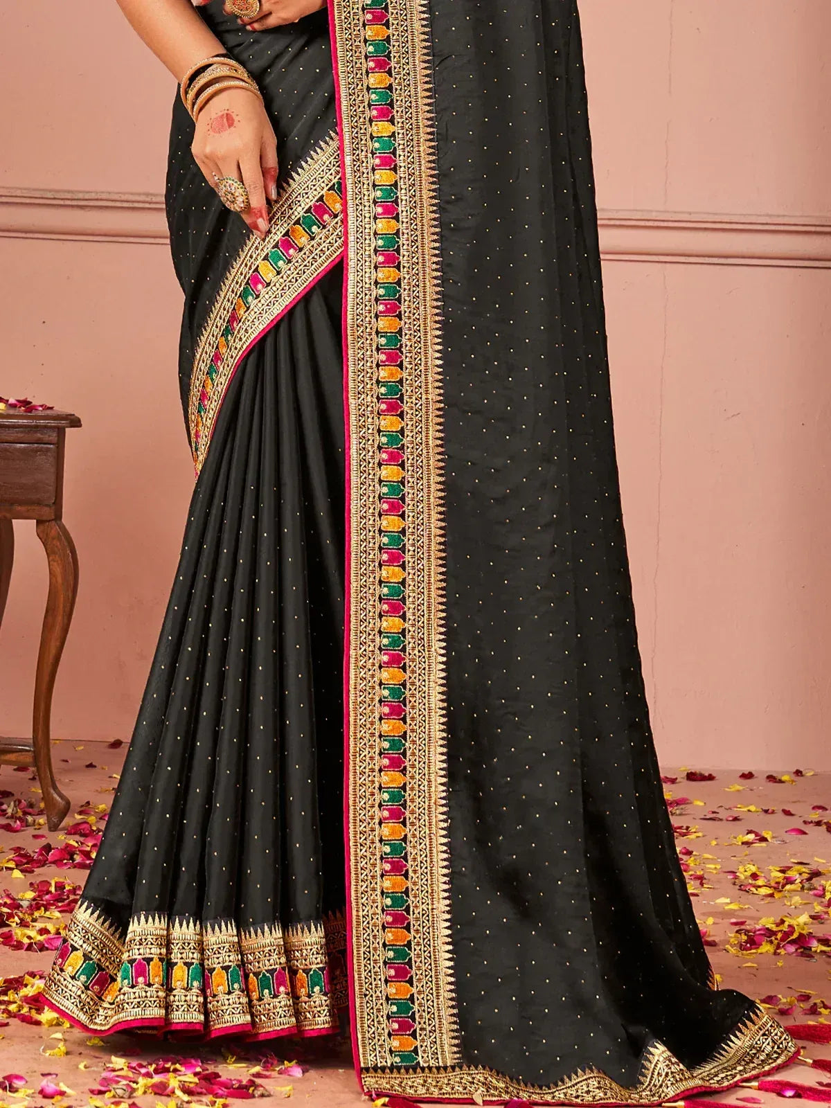 Black saree with colorful embroidered border and gold polka dots, perfect for ethnic occasions