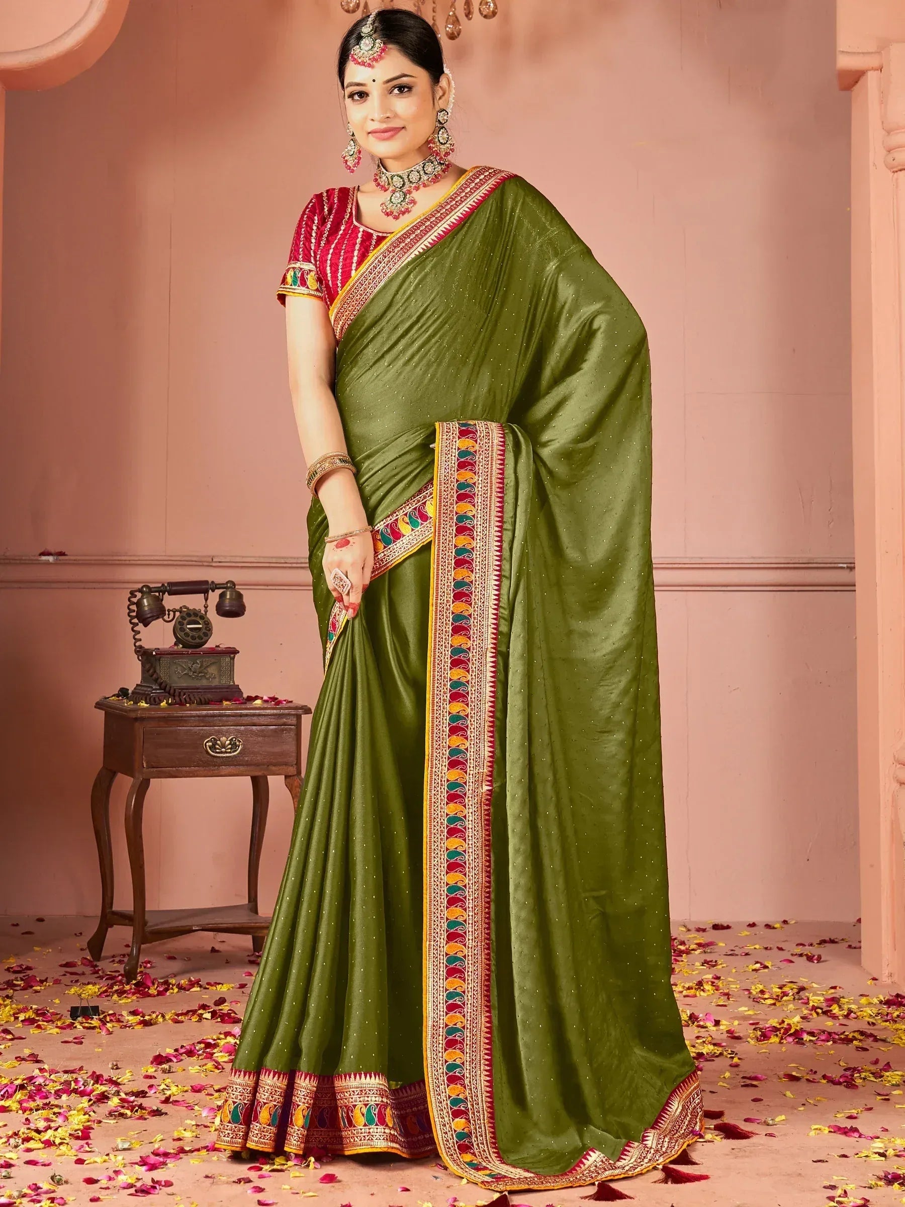 Olive green ethnic saree with colorful paisley border, paired with red blouse, perfect for Indian weddings or festivals