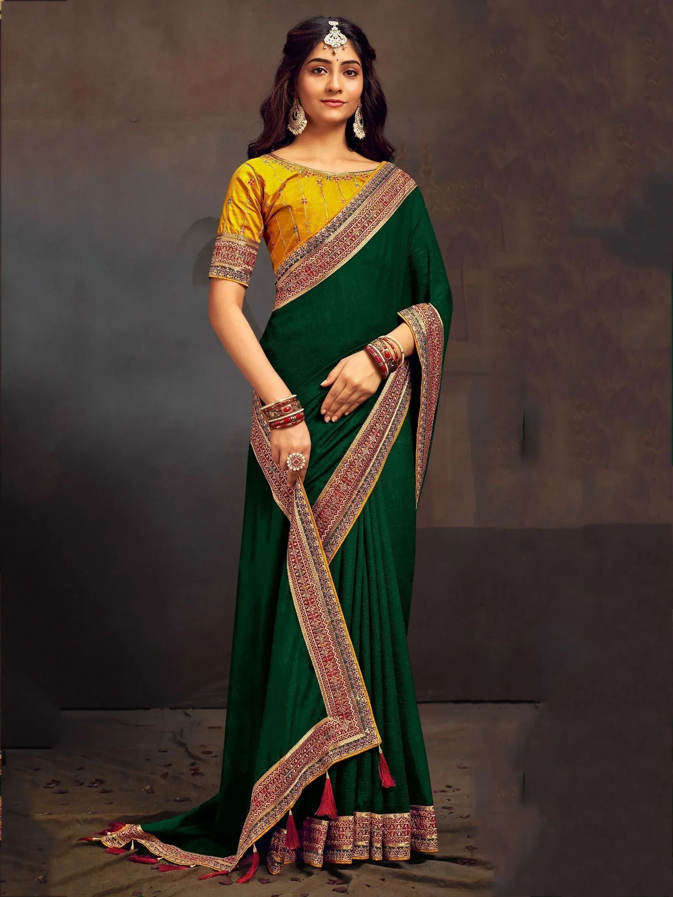 Woman in green and yellow designer saree with embroidered border and traditional jewelry