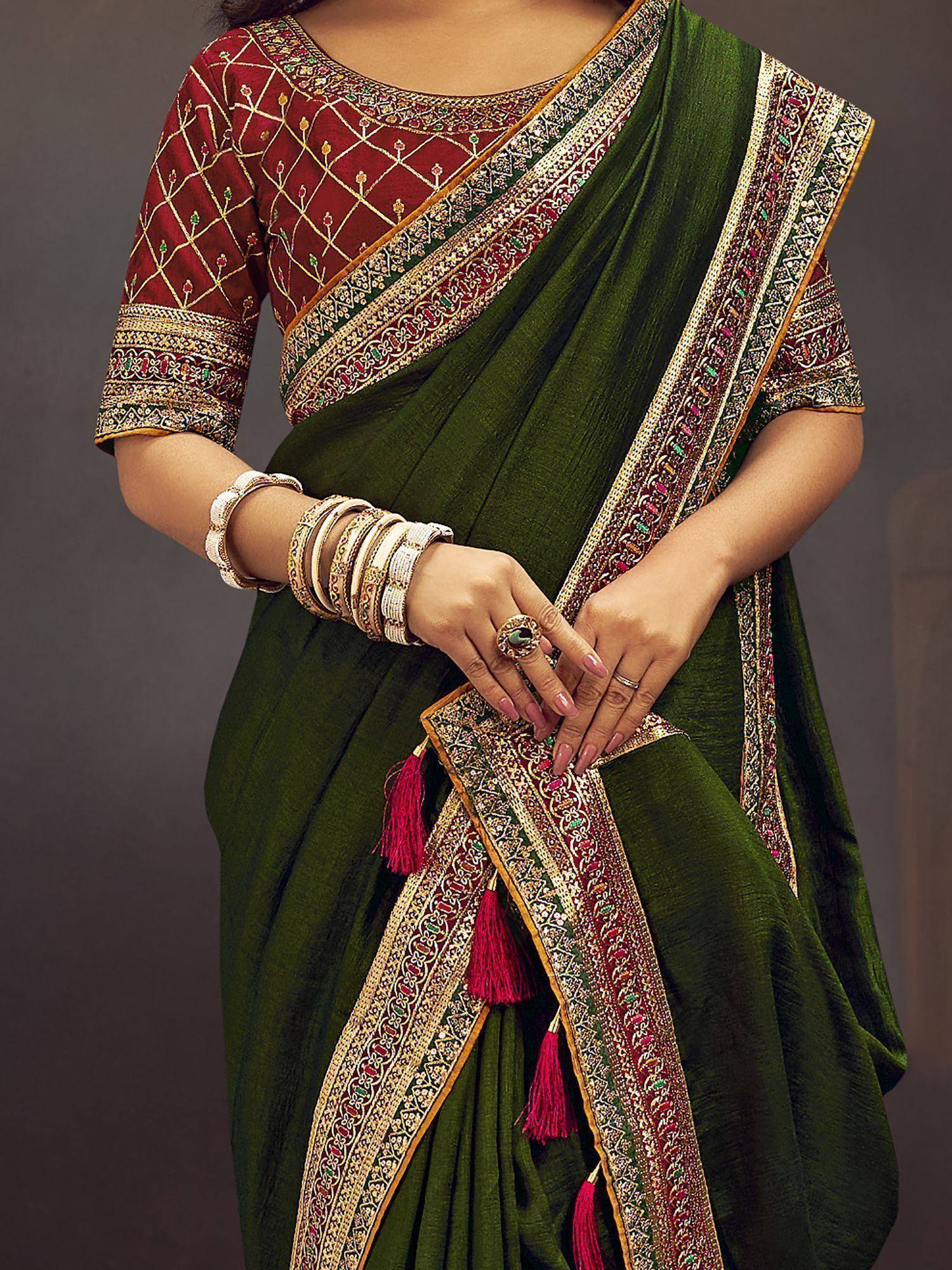 Emerald green saree with intricate gold and red border, paired with embroidered maroon blouse and tassels