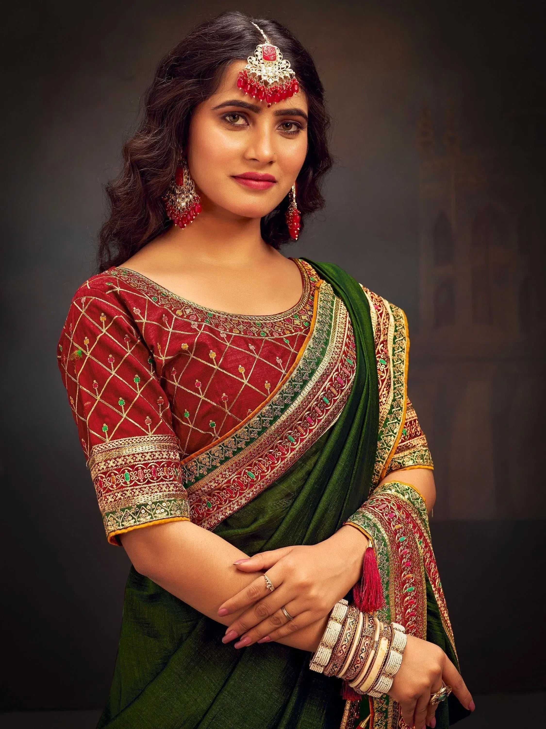 Woman in elegant green and red embroidered saree with traditional jewelry, perfect for Indian ethnic occasions.