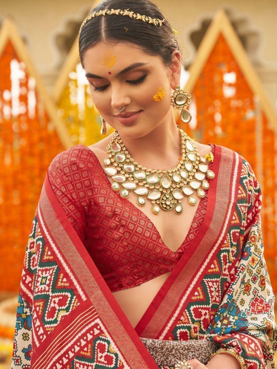 Woman in red ethnic saree with intricate patterns, gold jewelry, and traditional makeup for festive occasions