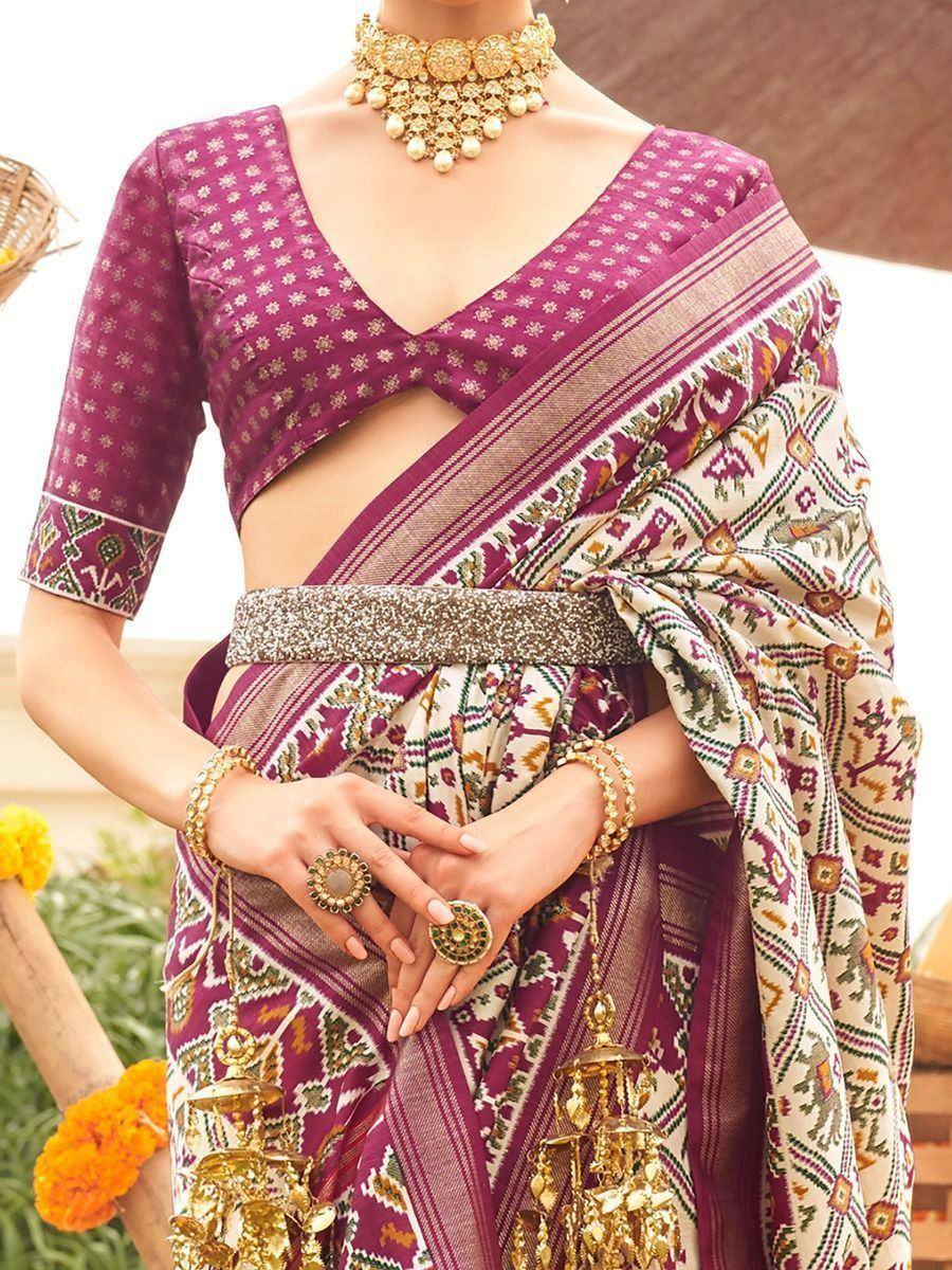 Purple printed saree with designer blouse, gold jewelry, and ethnic belt for Indian occasions