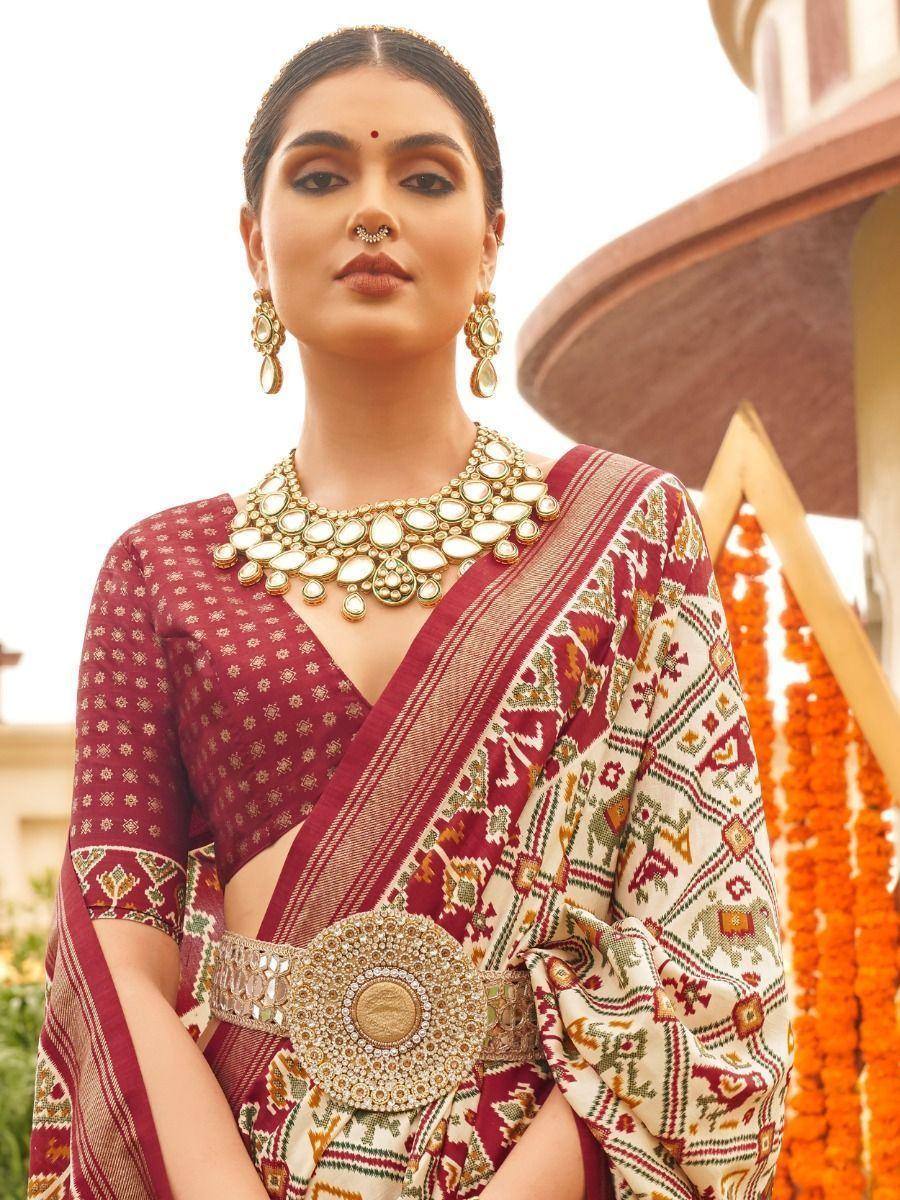 Woman in maroon and cream printed saree with gold jewelry, ethnic Indian wear