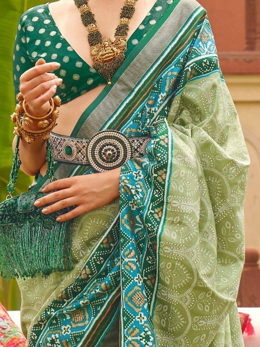 Green printed saree with polka dot blouse, ethnic jewelry, and embellished belt for Indian ethnic wear
