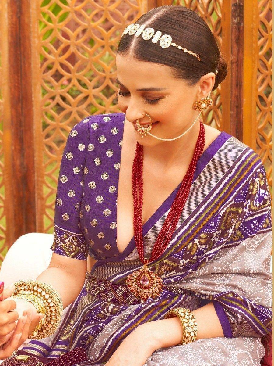 Woman in purple printed saree with gold jewelry, traditional Indian ethnic wear