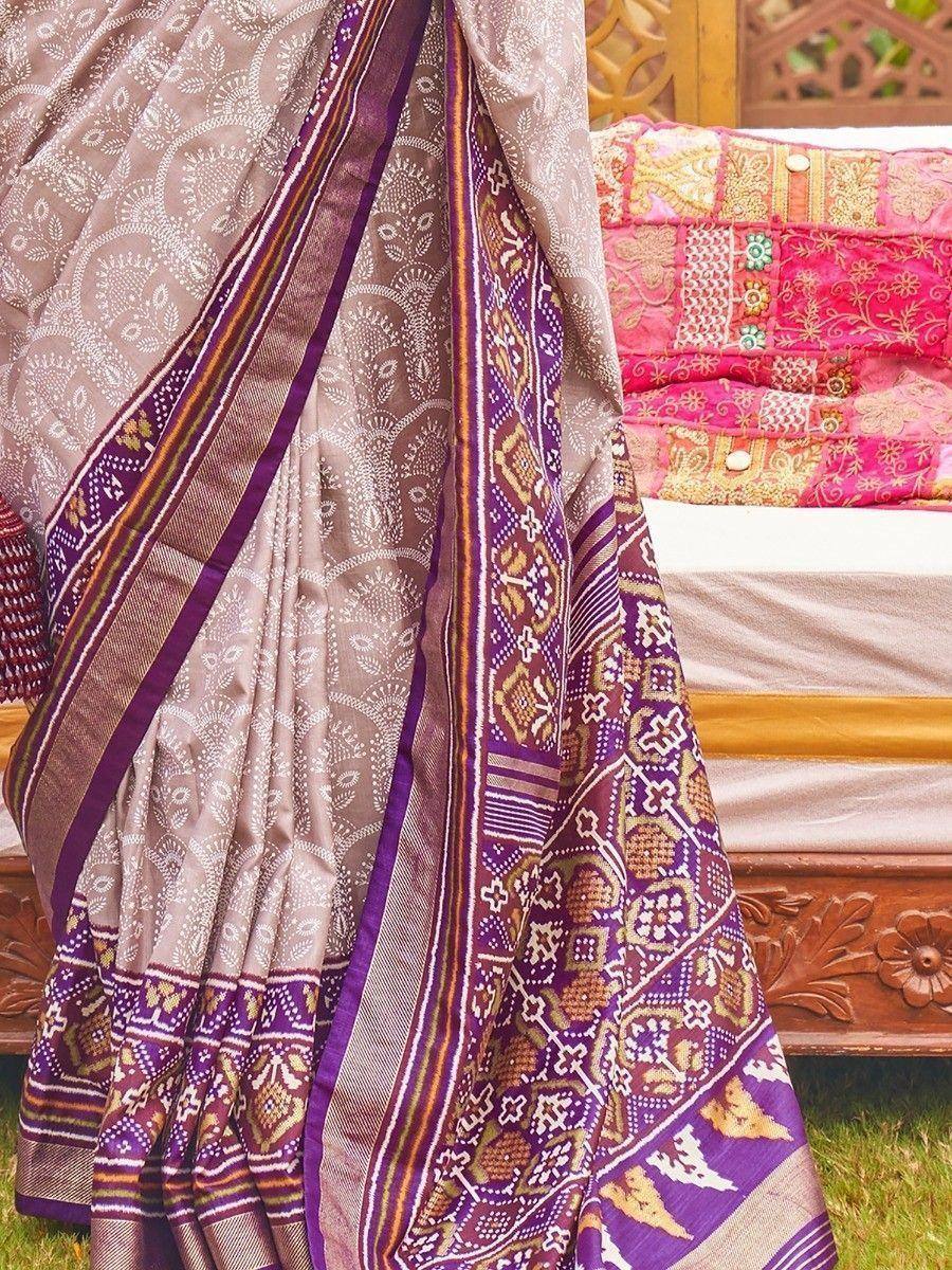 Purple and beige ethnic saree with intricate block print and woven border, styled on traditional wooden furniture