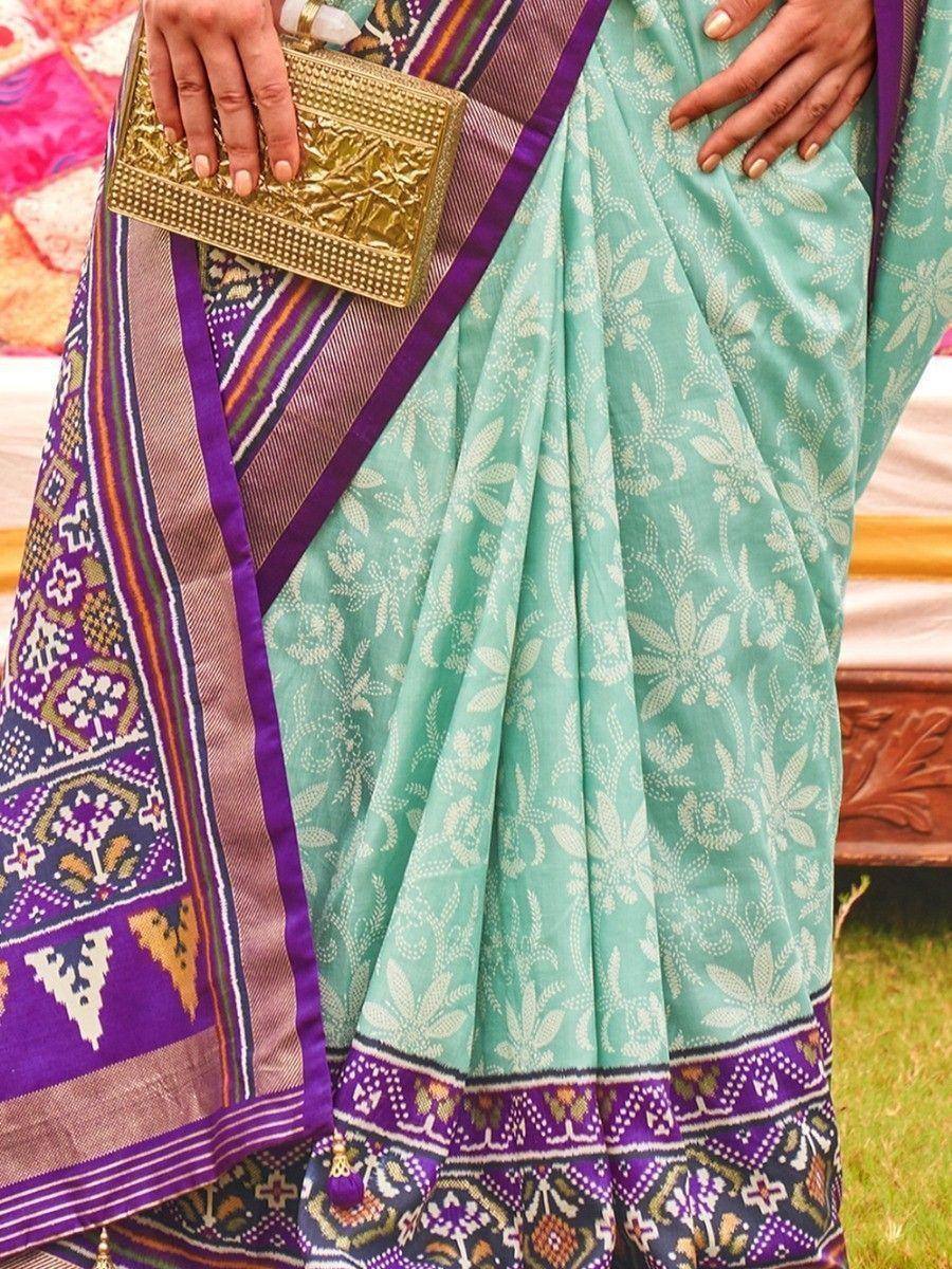 Mint green floral print saree with purple border, paired with gold clutch, ideal for ethnic occasions
