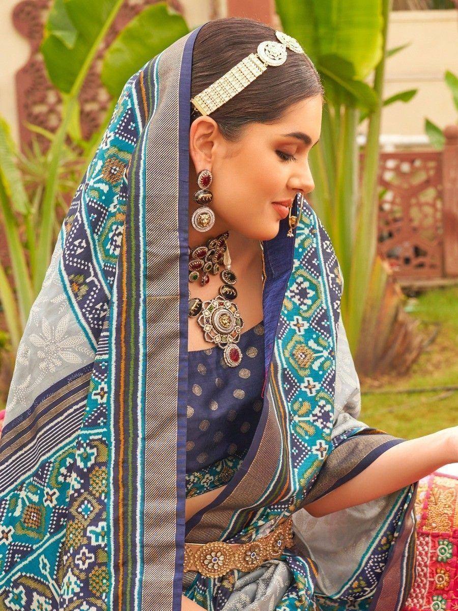 Woman in elegant blue and teal printed saree with gold jewelry, traditional Indian ethnic wear