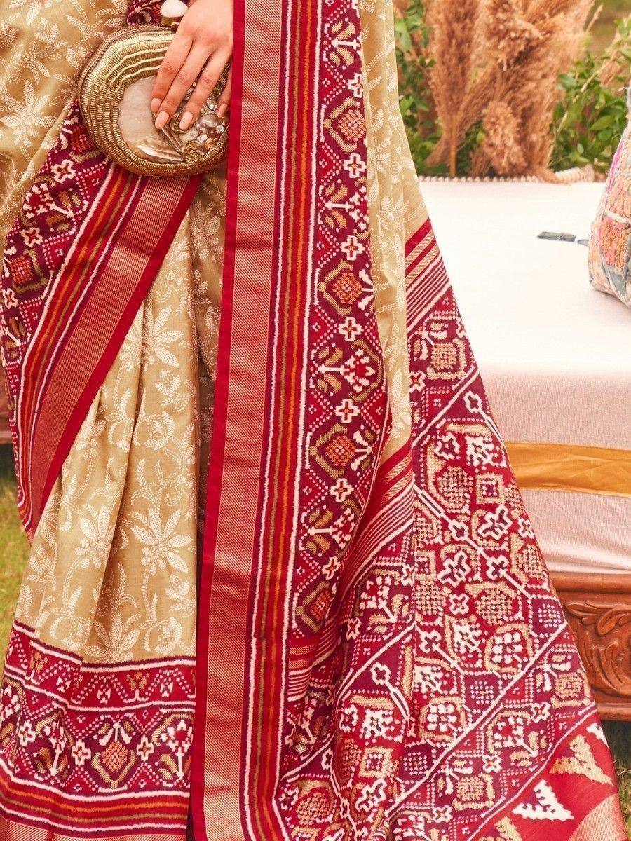 Elegant Indian saree with red and gold geometric patterns, paired with a matching clutch.
