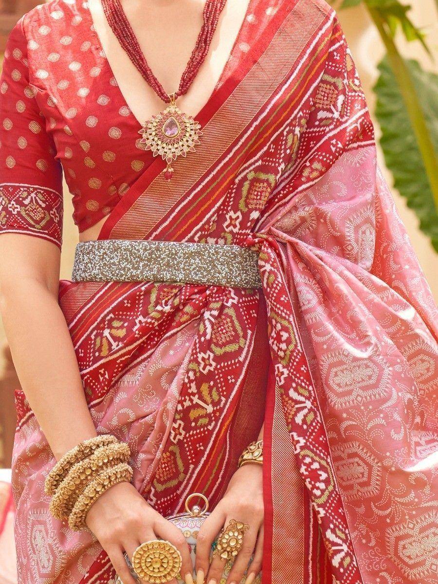 Red and pink ethnic saree with intricate patterns and gold jewelry